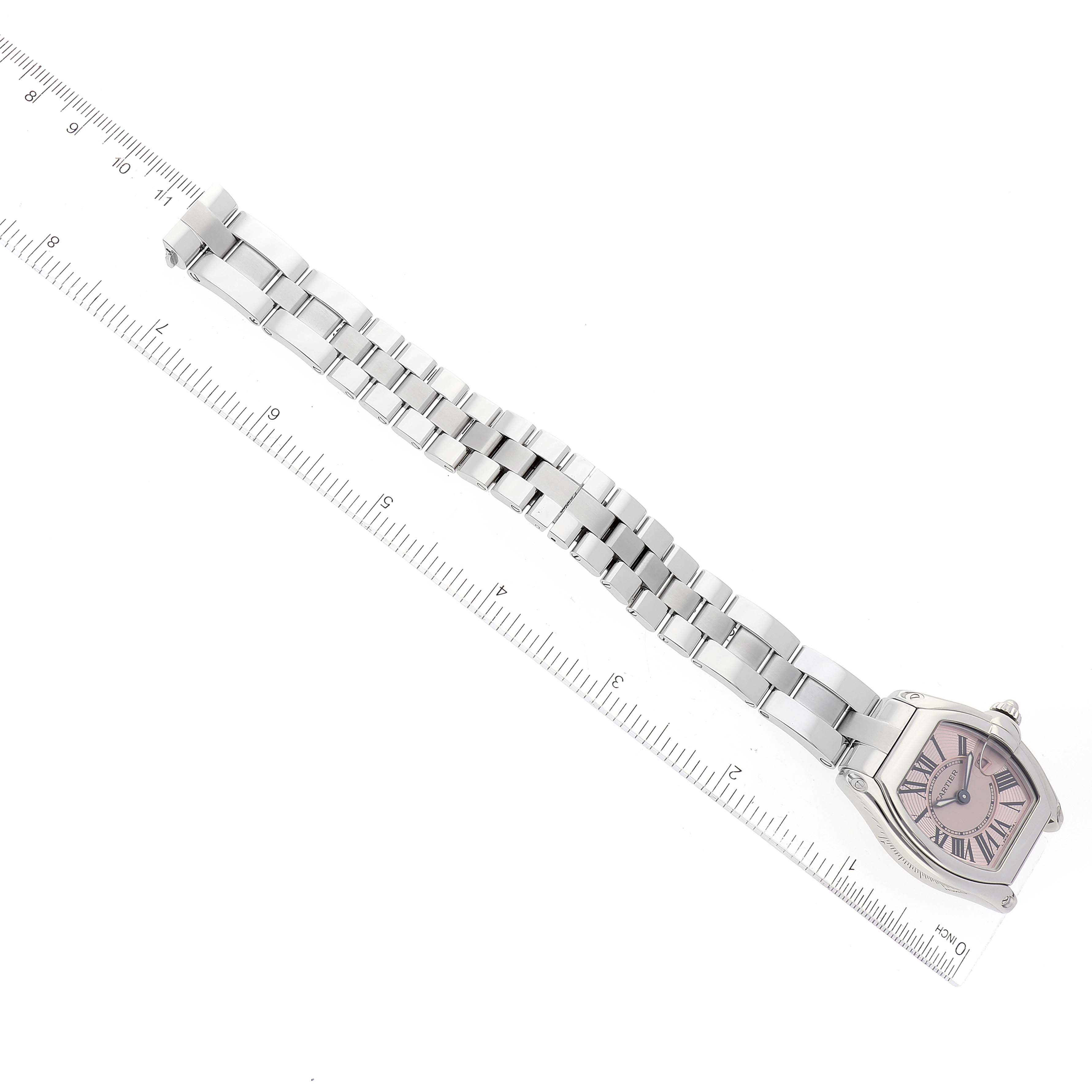 The image shows a top-down view of a Cartier Roadster W62017V3 Women's Stainless Steel Pink Dial W62017V3 Women's Stainless Steel Pink Dial watch with a stainless steel bracelet next to a ruler.
