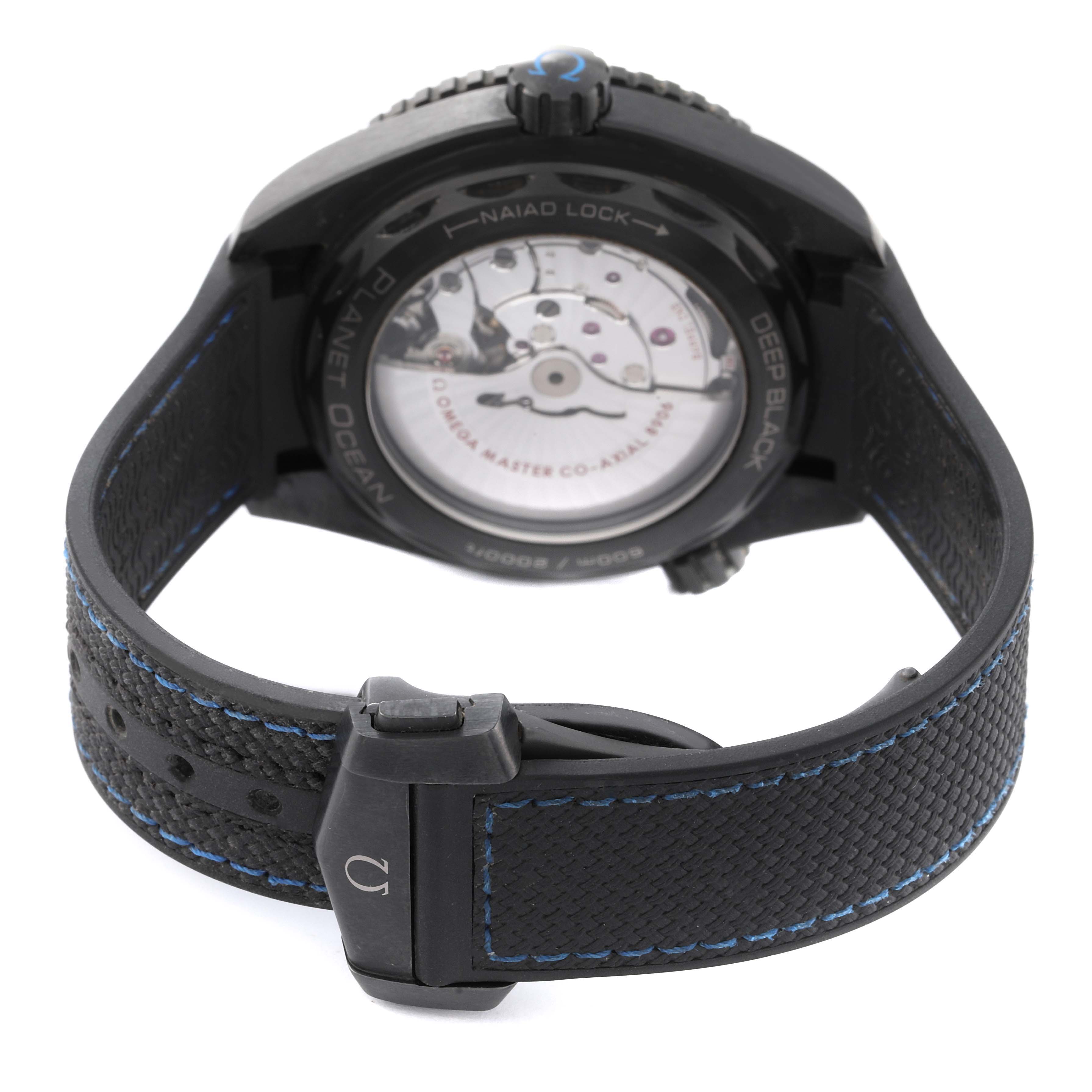 The image shows the back view of the Omega Planet Ocean 215.92.46.22.01.002 Men's Ceramic Black Dial 215.92.46.22.01.002 Men's Ceramic Black Dial watch, displaying its open case back and black strap with blue stitching.
