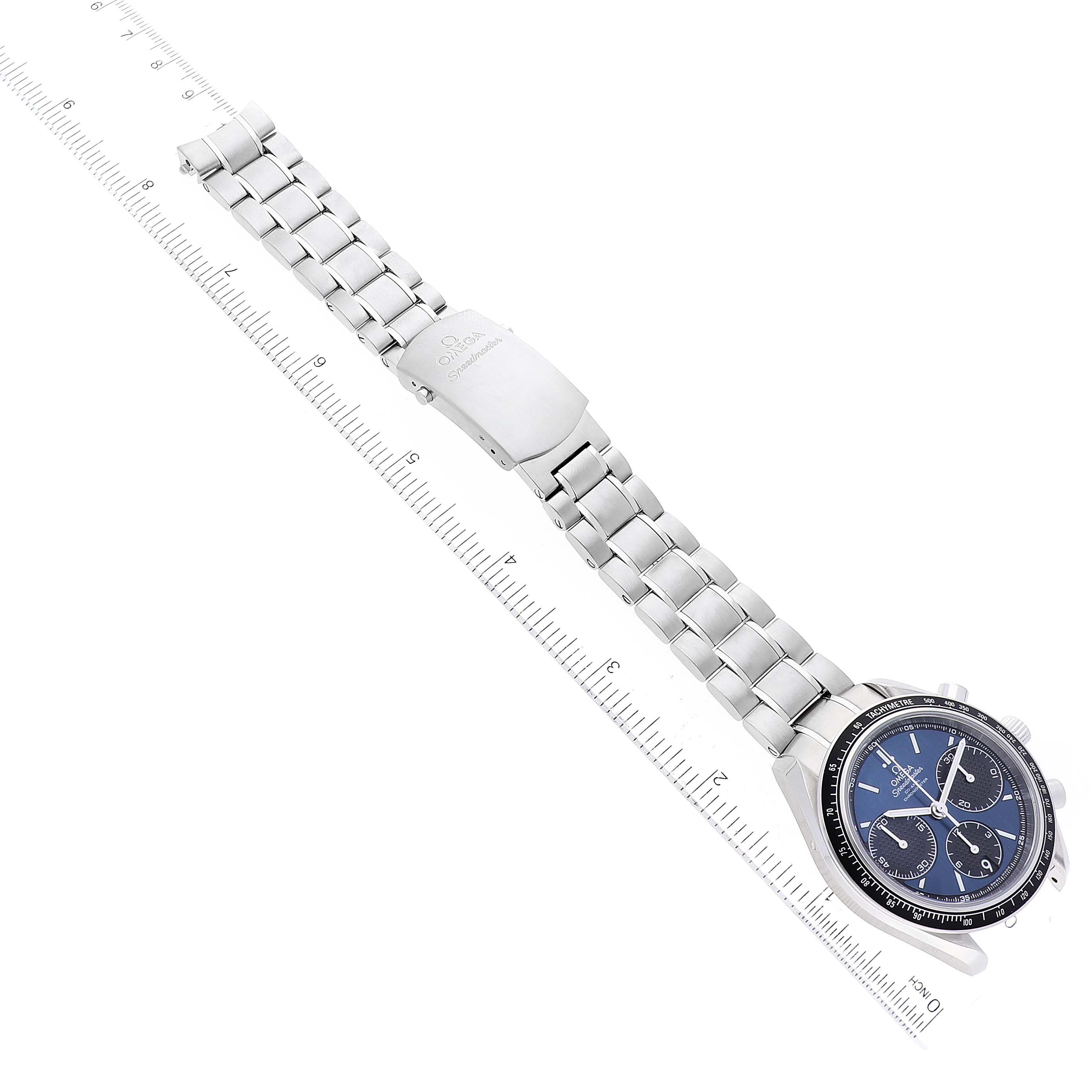 The image shows an Omega Speedmaster 326.30.40.50.03.001 Men
s Stainless Steel Blue Dial 326.30.40.50.03.001 Men
s Stainless Steel Blue Dial watch lying flat, showcasing its face, bracelet, and clasp, placed beside a ruler.