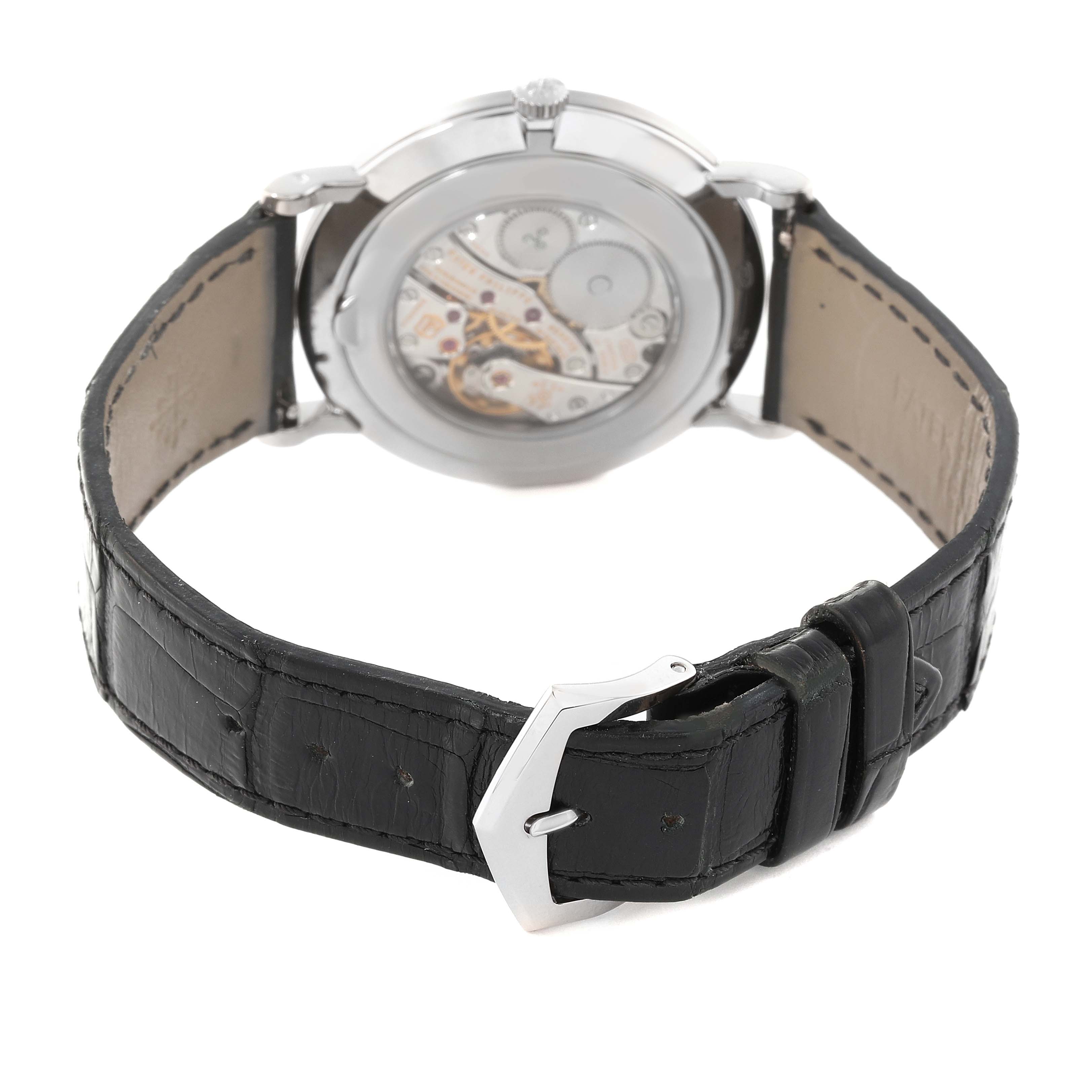 The image shows the back view of a Patek Philippe Calatrava 5119G-001 Men
s White Gold White Dial 5119G-001 Men
s White Gold White Dial watch, highlighting its transparent case back, leather strap, and clasp.