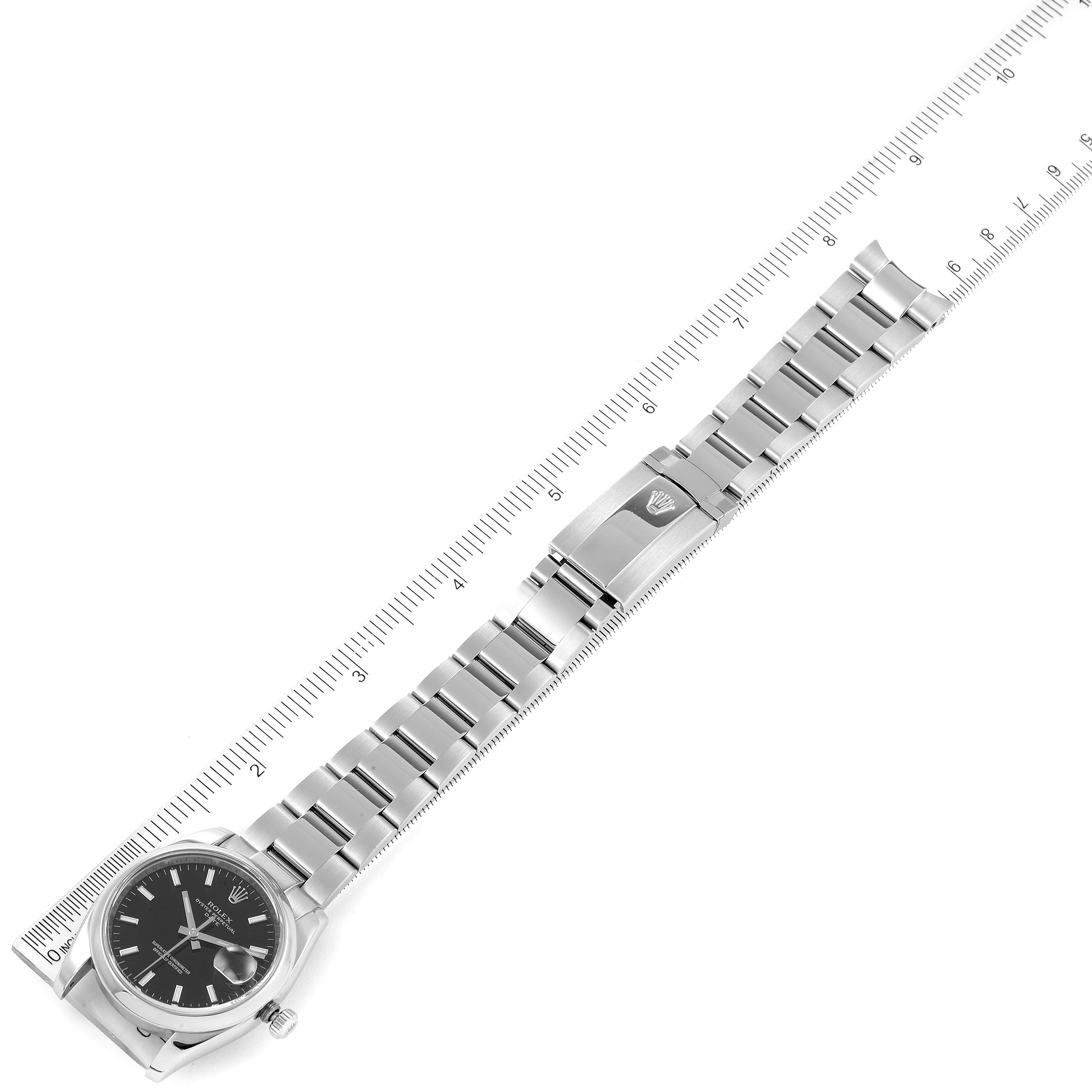 This image shows a flat-lay view of the Rolex Date 115200 Men's Stainless Steel Black Dial 115200 Men's Stainless Steel Black Dial model watch, displaying the bracelet, clasp, and watch face next to a ruler.