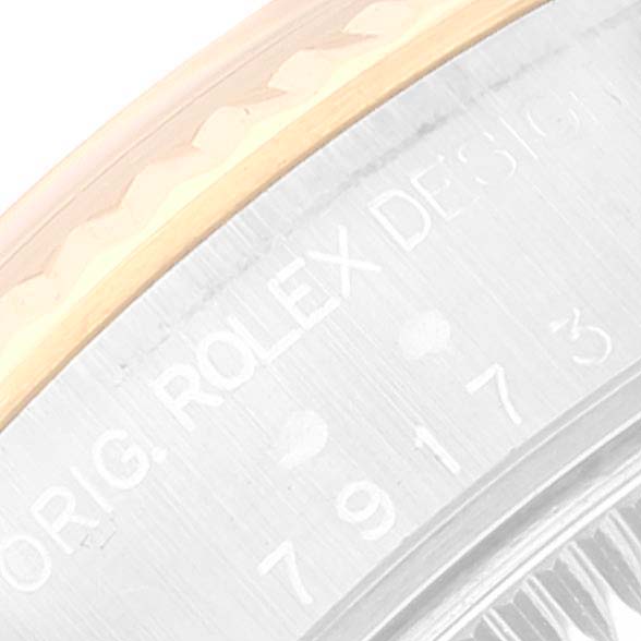 This image shows a close-up of the side of a Rolex Datejust 79173 Women's Steel and Gold (two tone) Champagne Dial 79173 Women's Steel and Gold (two tone) Champagne Dial's case with engraved text and part of the bezel.