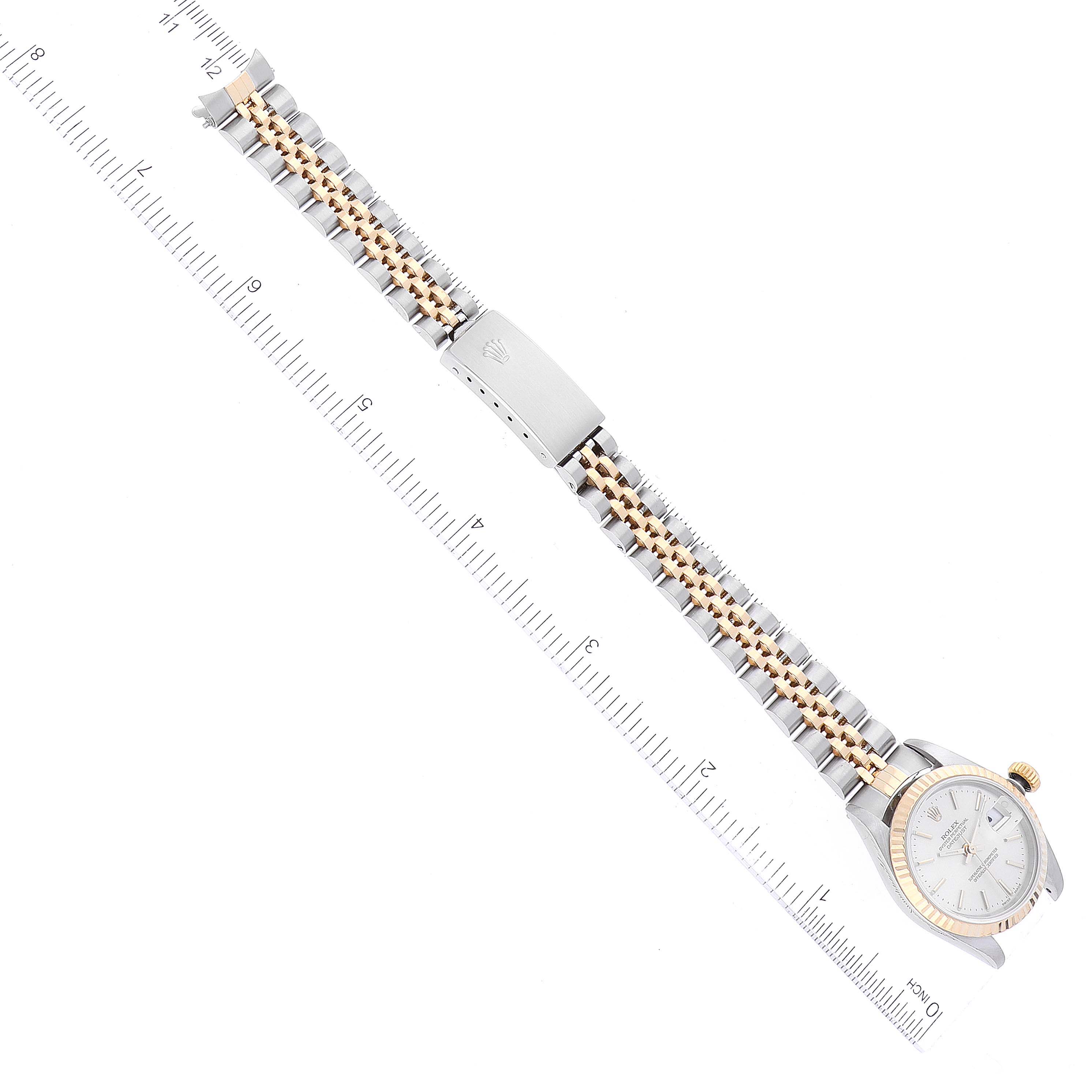 The image shows a top-down view of a Rolex Datejust 79173 Women's Steel and Gold (two tone) Silver Dial 79173 Women's Steel and Gold (two tone) Silver Dial watch with the band extended next to a ruler for scale.