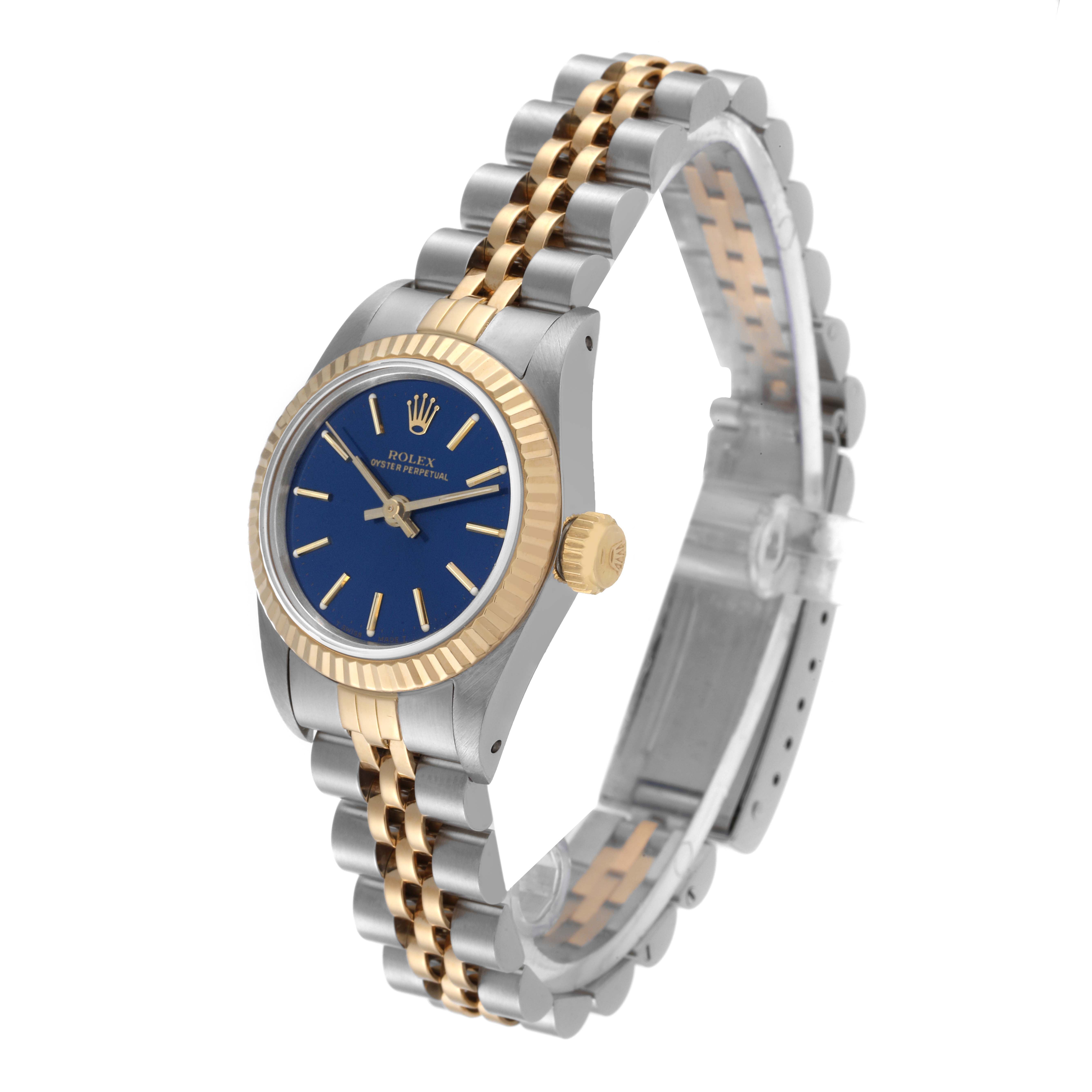 This Rolex Oyster Perpetual 67193 Women's Steel and Gold (two tone) Blue Dial 67193 Women's Steel and Gold (two tone) Blue Dial watch is shown in a three-quarter view, displaying its two-tone bracelet, blue dial, and fluted bezel.