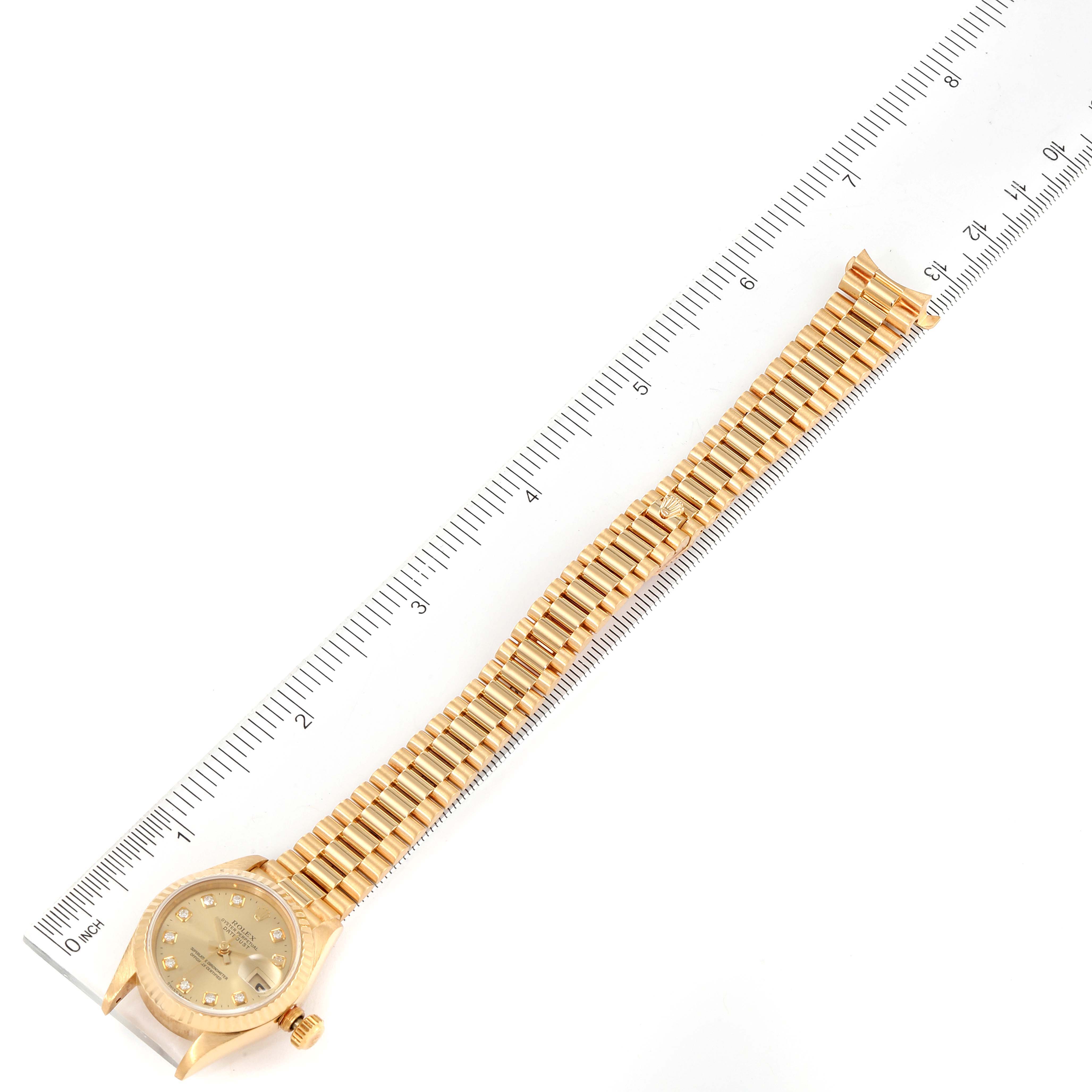 The Rolex President 69178 Women
s Yellow Gold Champagne Dial 69178 Women
s Yellow Gold Champagne Dial model watch is photographed from a top-down angle, showing the face, crown, and bracelet next to a ruler.