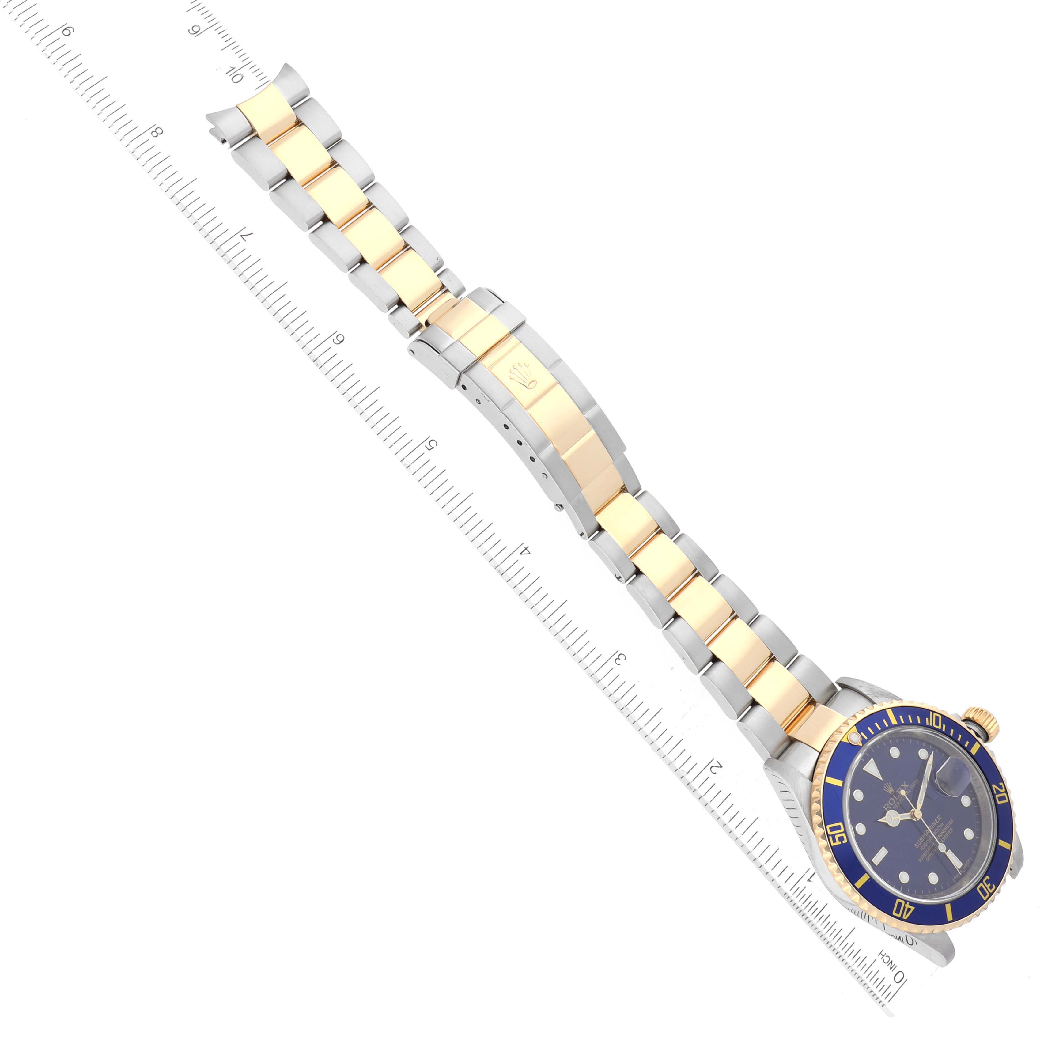 The image shows the Rolex Submariner 16613 Men's Steel and Gold (two tone) Blue Dial 16613 Men's Steel and Gold (two tone) Blue Dial watch at an overhead angle, emphasizing its bracelet with gold center links and clasp.