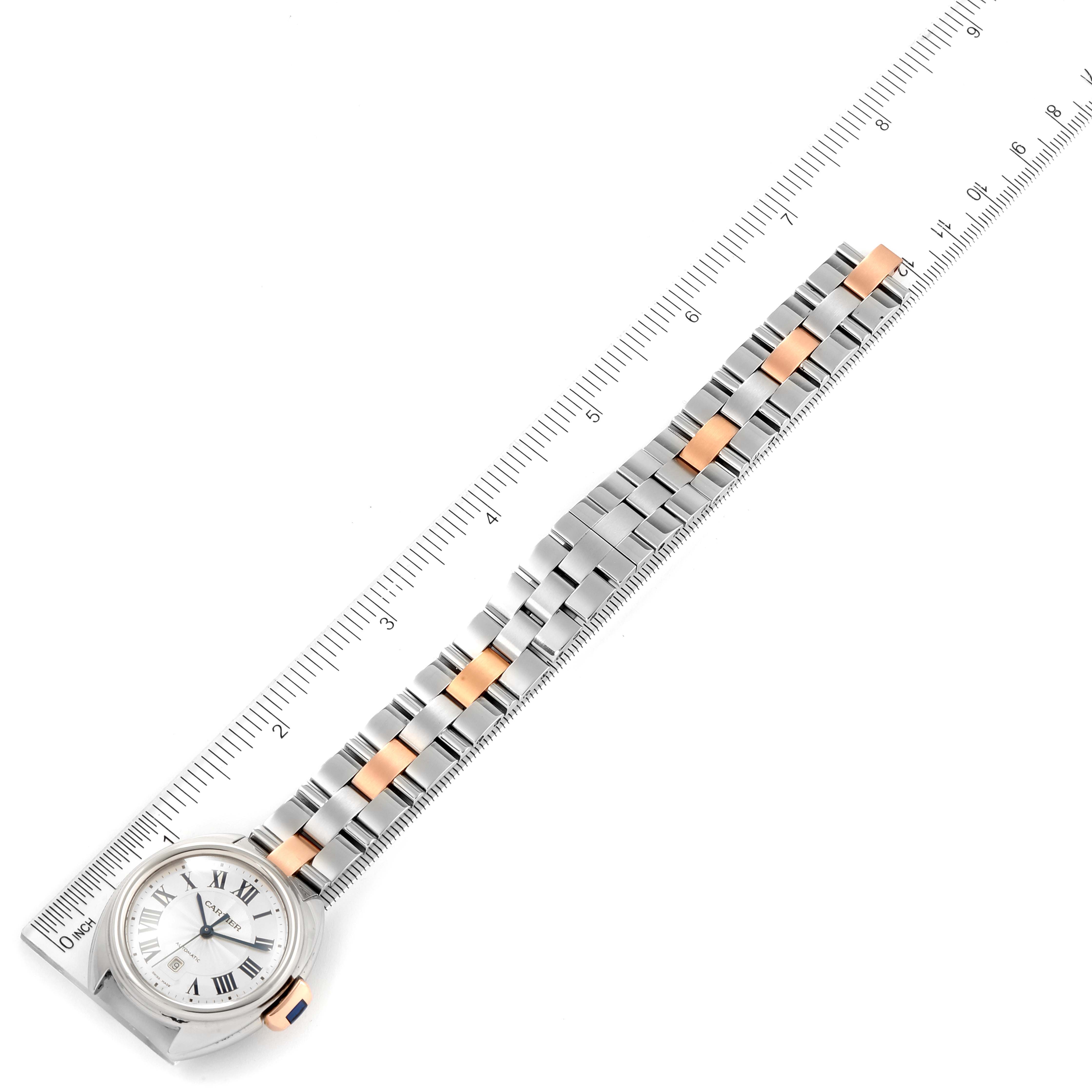 The Cle de Cartier watch is shown from a top-down angle, displaying the face, bezel, and full bracelet placed next to a ruler.