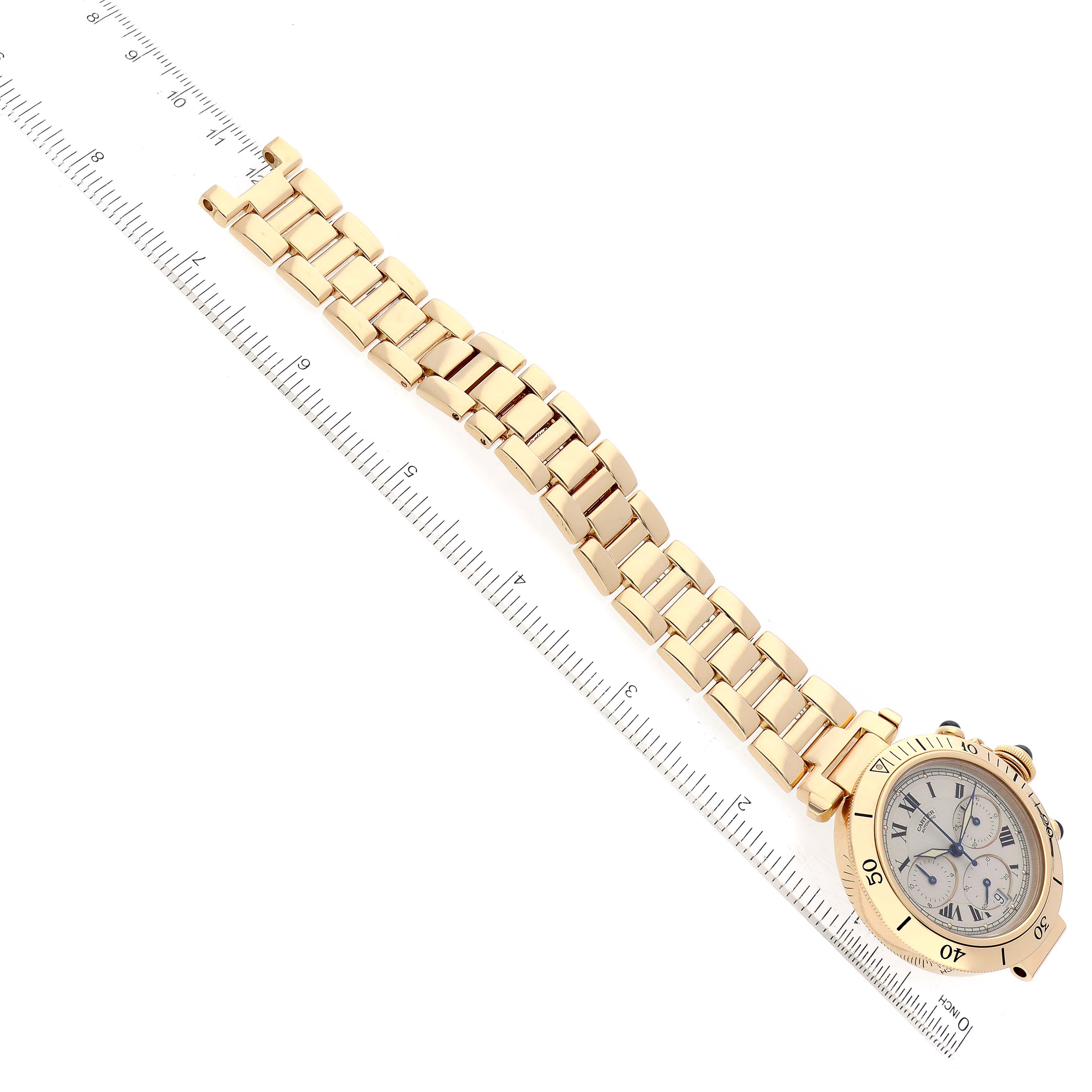 This image shows the Cartier Pasha W524428 Men
s Yellow Gold Silver Dial W524428 Men
s Yellow Gold Silver Dial watch at an oblique angle, featuring its bracelet, bezel, and watch face alongside a ruler.