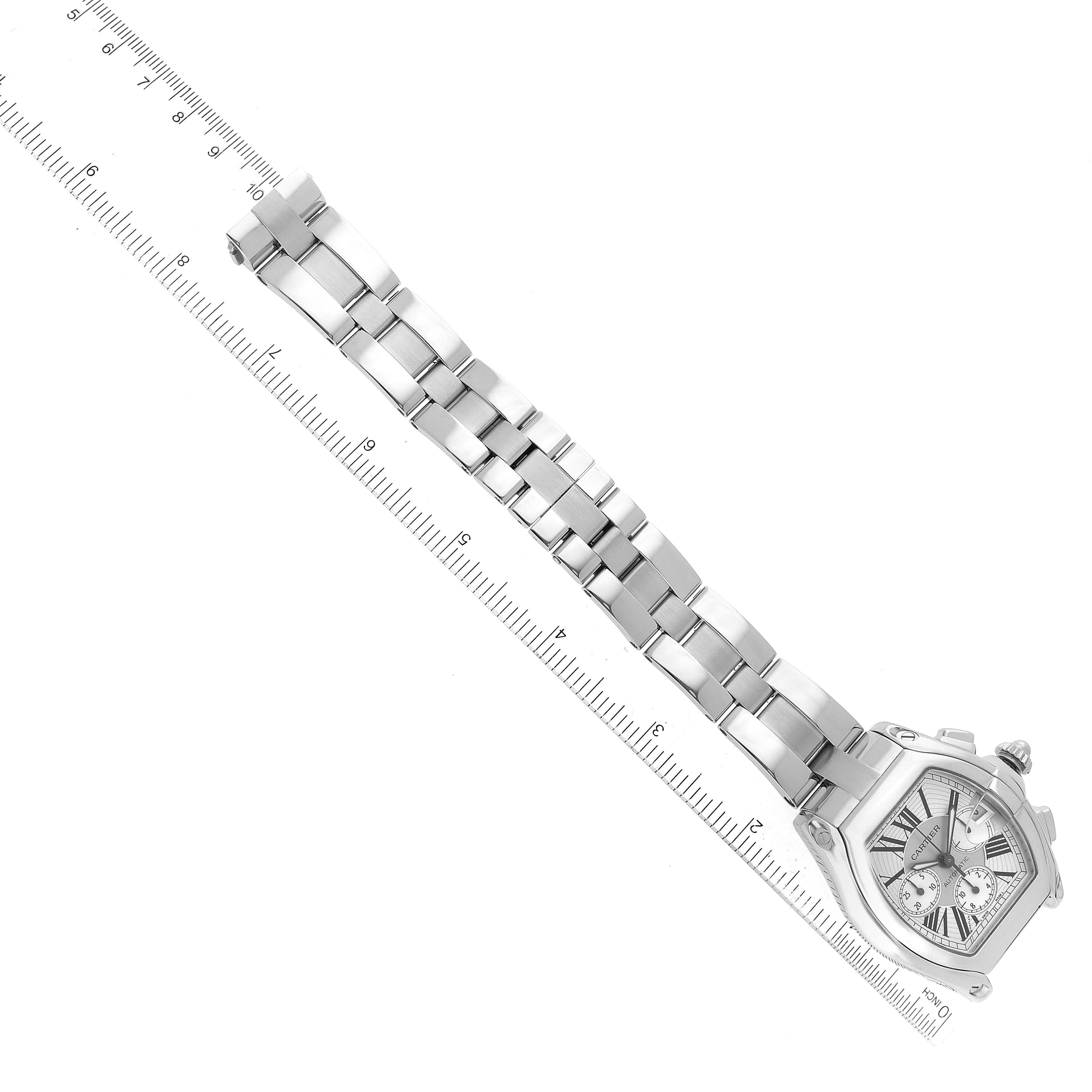 This is a top-down view of a Cartier Roadster W62019X6 Men
s Stainless Steel Silver Dial W62019X6 Men
s Stainless Steel Silver Dial watch showing the face, bezel, and entire bracelet band alongside a ruler.