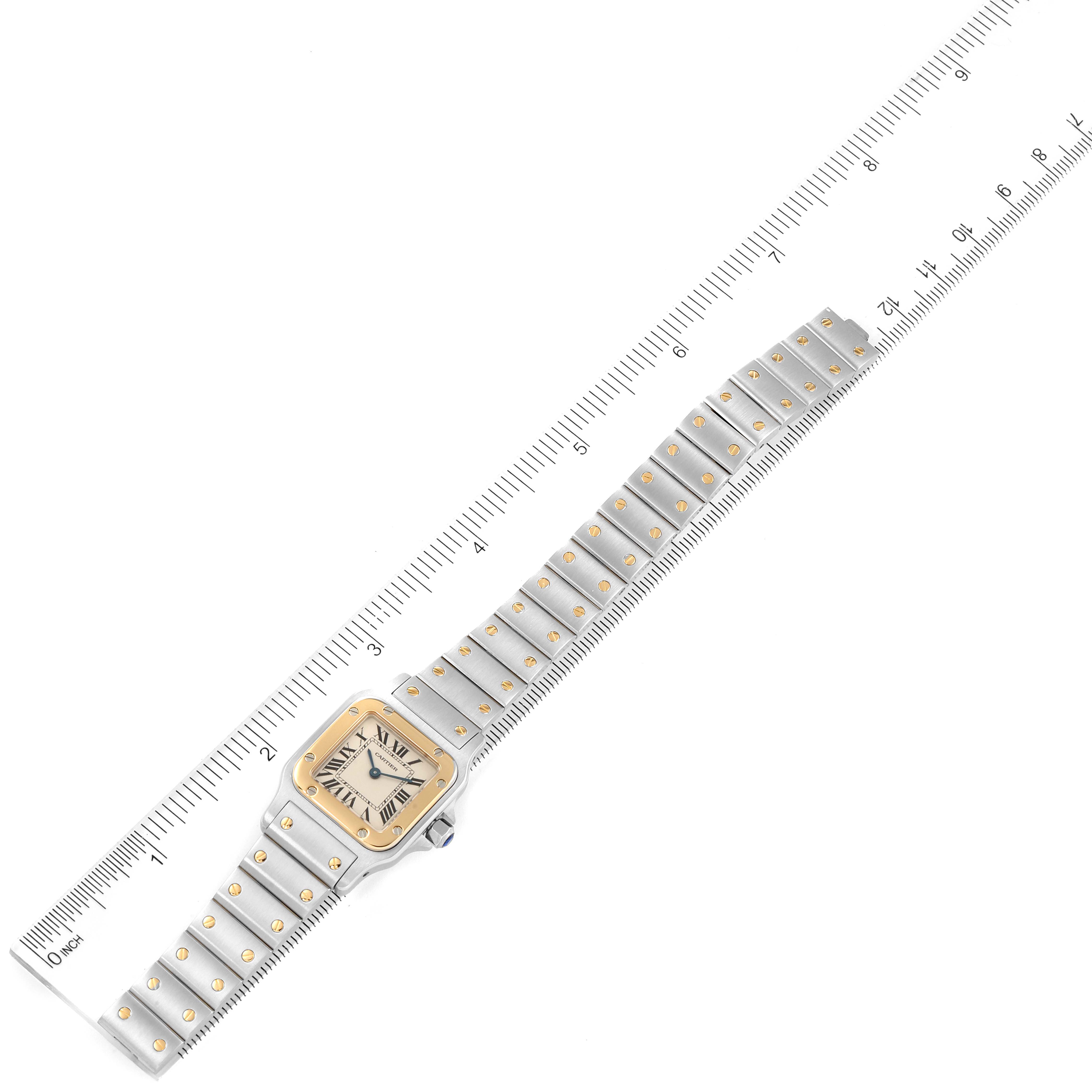 The Cartier Santos W20012C4 Women's Steel and Gold (two tone) Silver Dial W20012C4 Women's Steel and Gold (two tone) Silver Dial watch is shown laid flat next to a ruler, displaying the face and entire bracelet in full length.