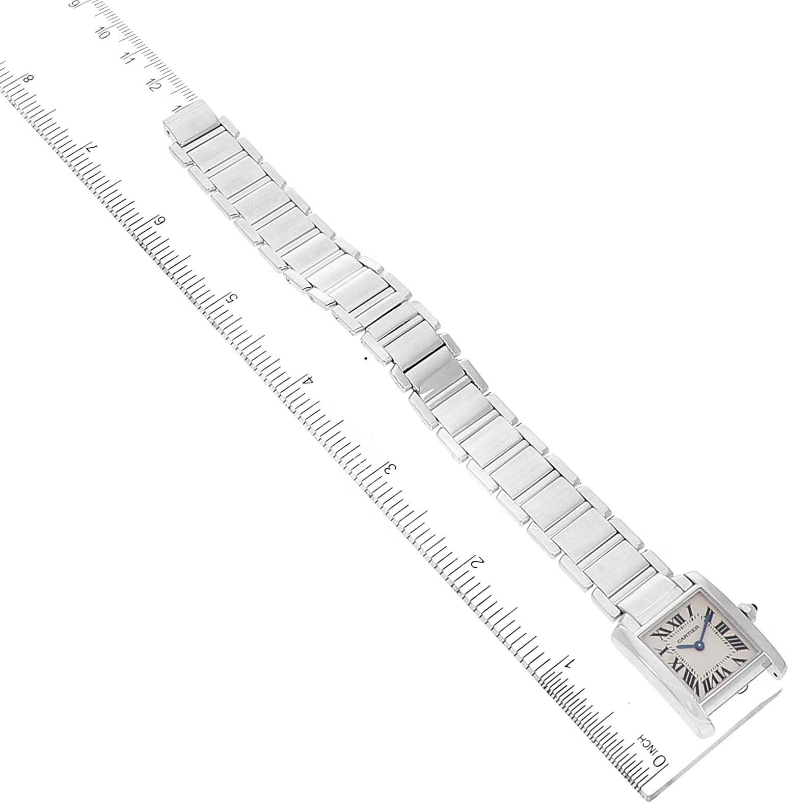The Cartier Tank Francaise W50012S3 Women's White Gold Silver Dial W50012S3 Women's White Gold Silver Dial watch is shown from an overhead angle, displaying its rectangular face, bracelet, and a ruler for scale.