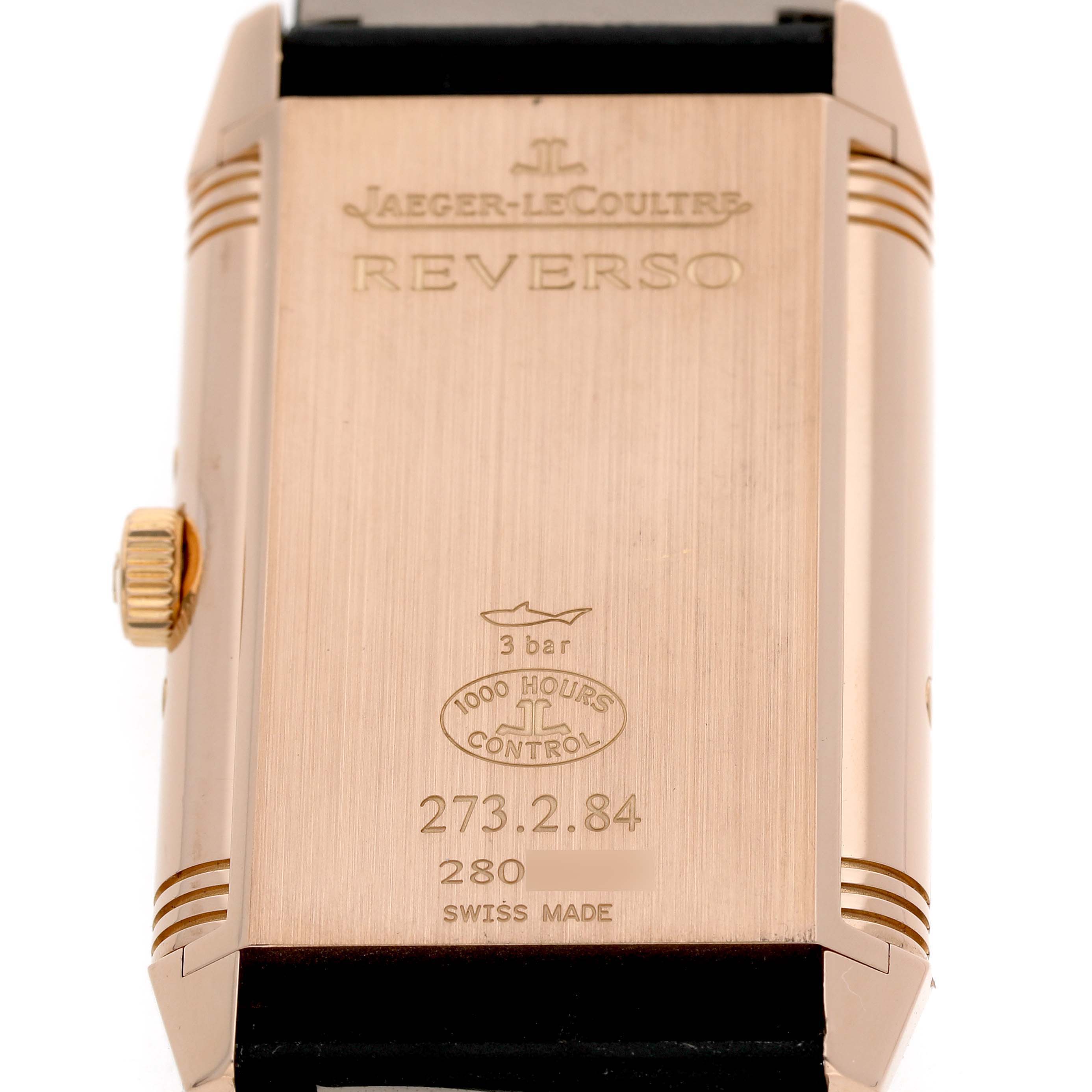 The image shows the back case of a Jaeger-LeCoultre Reverso watch, displaying engravings and the crown on the side.