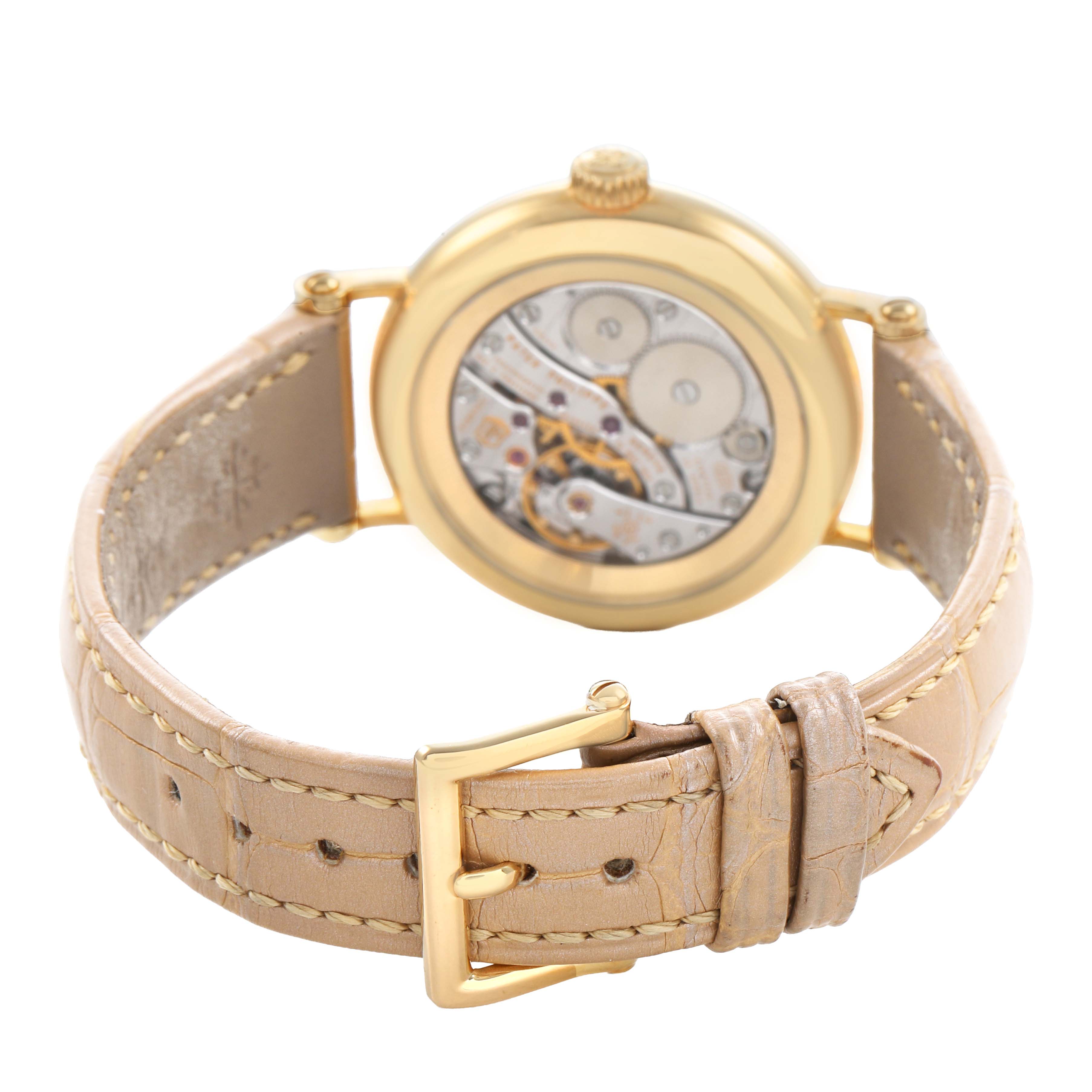 The Patek Philippe Calatrava 7121J-001 Women's Yellow Gold Silver Dial watch is shown from the back, revealing the movement and beige leather strap with a gold buckle.