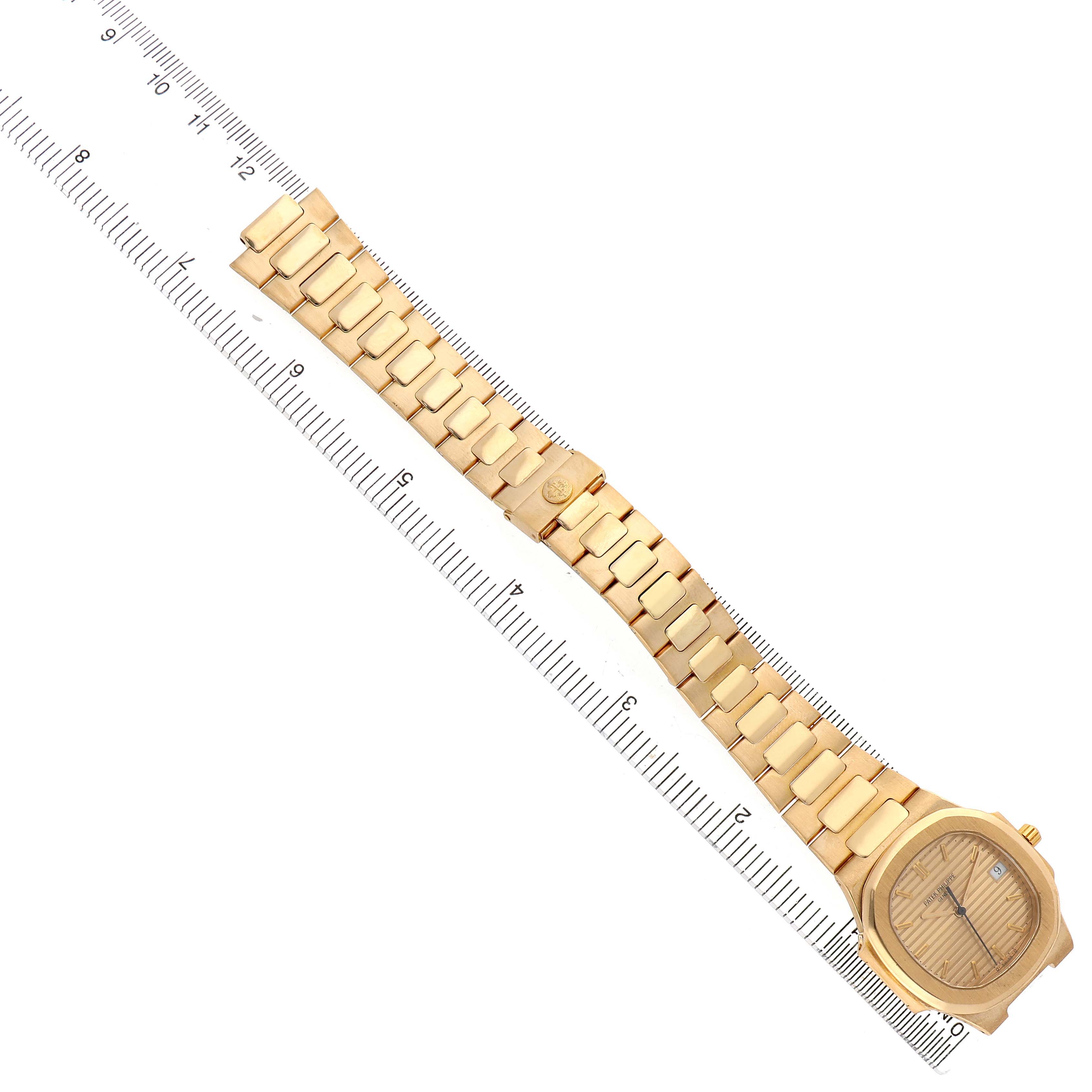 The Patek Philippe Nautilus 3900/1J Women's Yellow Gold Champagne Dial watch is shown from above, displaying the bracelet, case, and dial alongside a ruler.