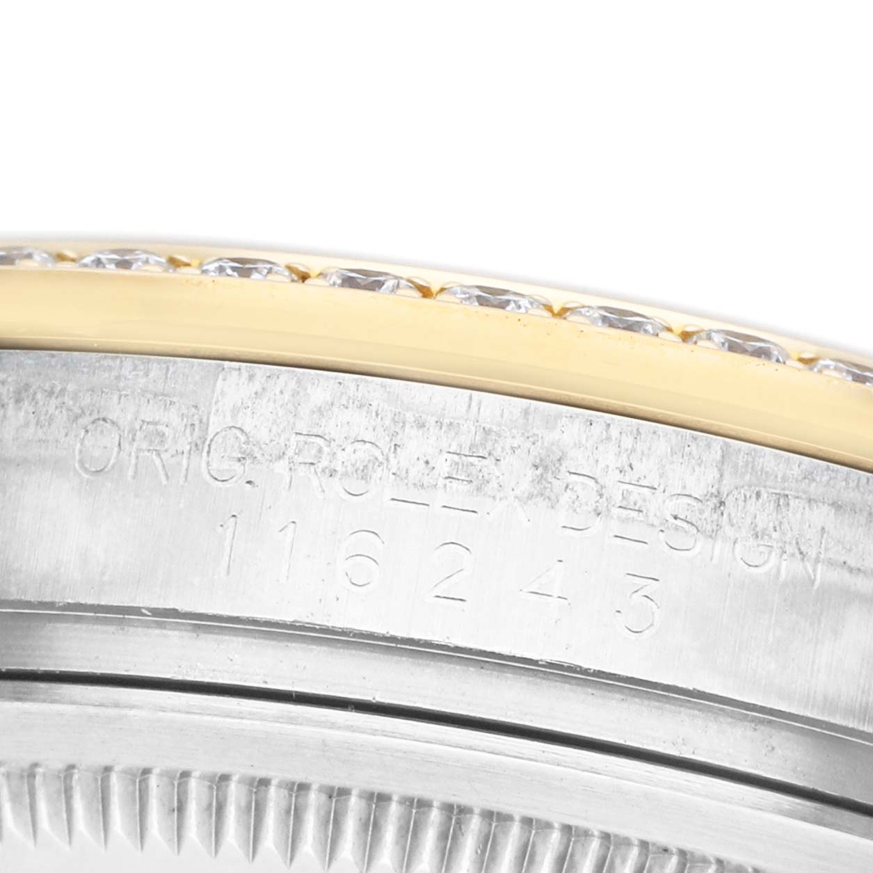 The image shows a close-up of the side of a Rolex Datejust 116243 Men's Steel and Gold (two tone) Champagne Dial, focusing on the bezel and case with engraved text and diamond accents.