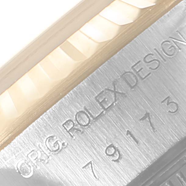 This close-up image shows the engraved edge of a Rolex Datejust 79173 Women's Steel and Gold (two tone) Blue Dial 79173 Women's Steel and Gold (two tone) Blue Dial watch, highlighting the serial number and part of the fluted bezel.