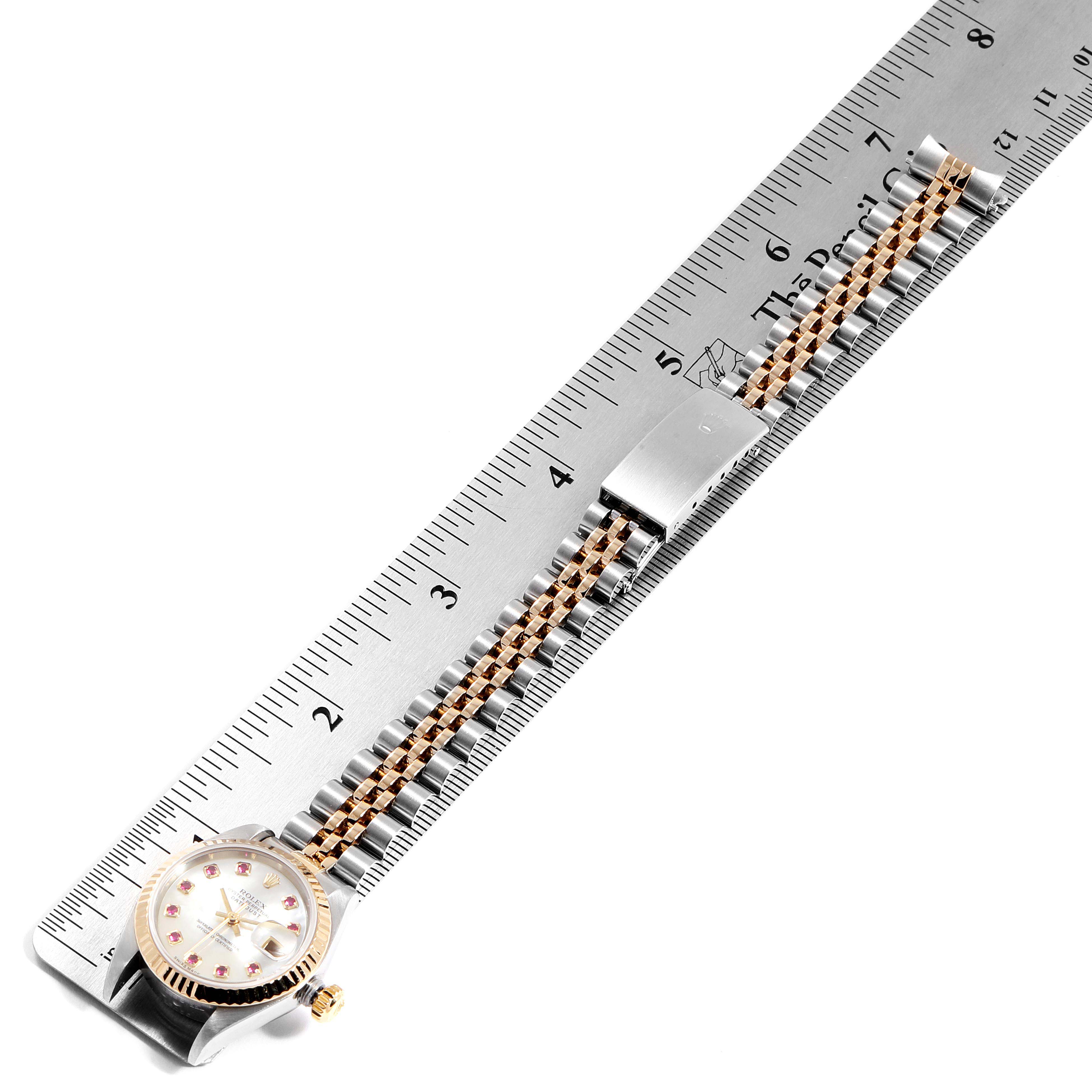 The Rolex Datejust 79173 Women
s Steel and Gold (two tone) Mother of Pearl Dial 79173 Women
s Steel and Gold (two tone) Mother of Pearl Dial watch is shown from a top-down angle, with the face and full length of the band visible against a ruler.