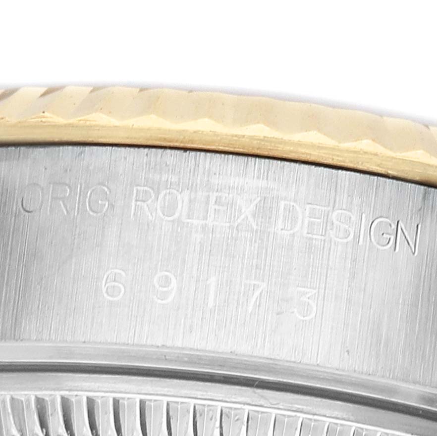 The image shows a partial close-up of the side of a Rolex Datejust 69173 Women's Steel and Gold (two tone) White Dial, featuring the case with engraved text and part of the bezel.