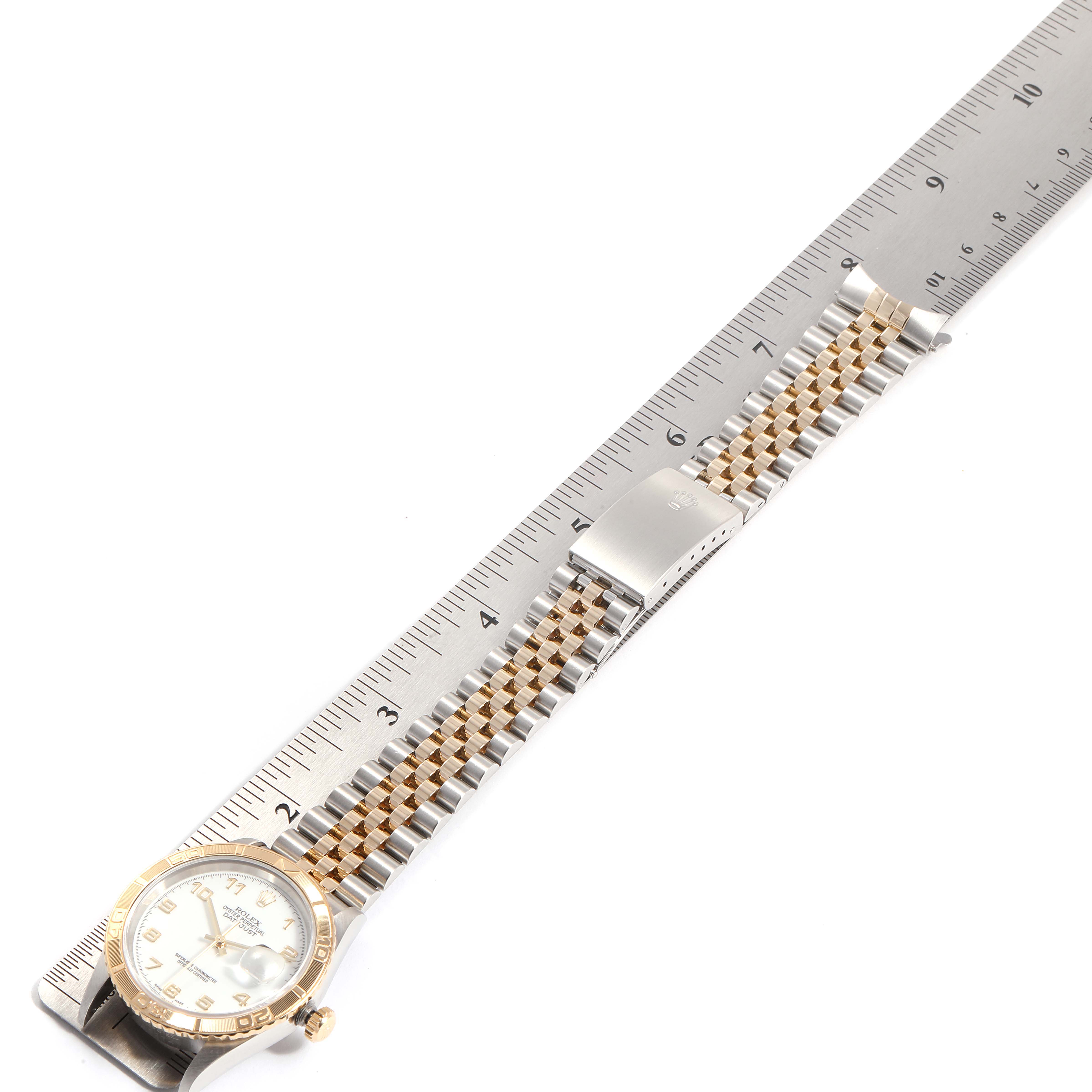 The Rolex Turn-o-Graph 16263 Men
s Steel and Gold (two tone) White Dial 16263 Men
s Steel and Gold (two tone) White Dial watch is shown from above, displaying its face, bezel, and bracelet placed beside a ruler for scale.