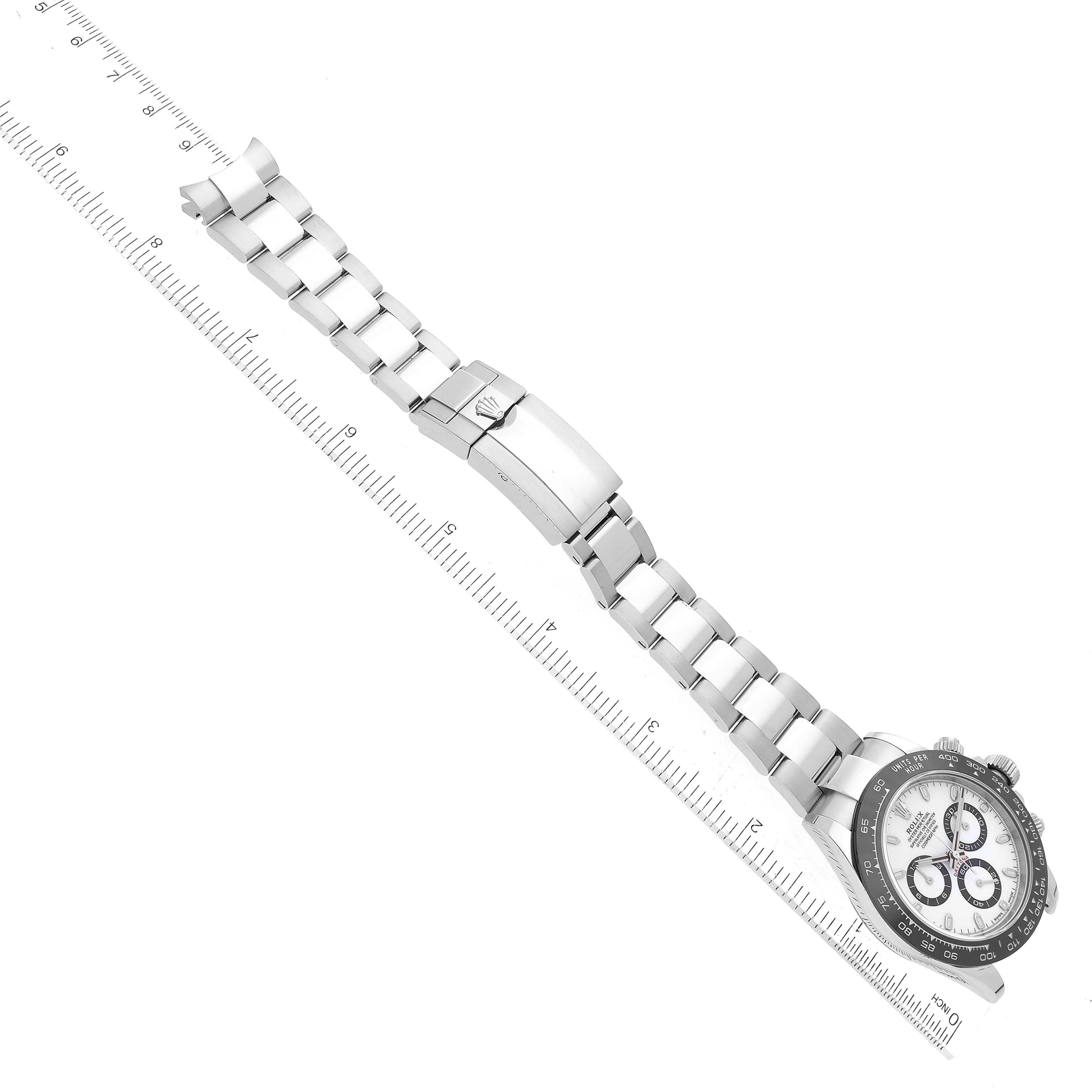 The image shows a top-down view of a Rolex Daytona 116500 Men's Stainless Steel White Dial 116500 Men's Stainless Steel White Dial watch with its band extended alongside a ruler for scale.
