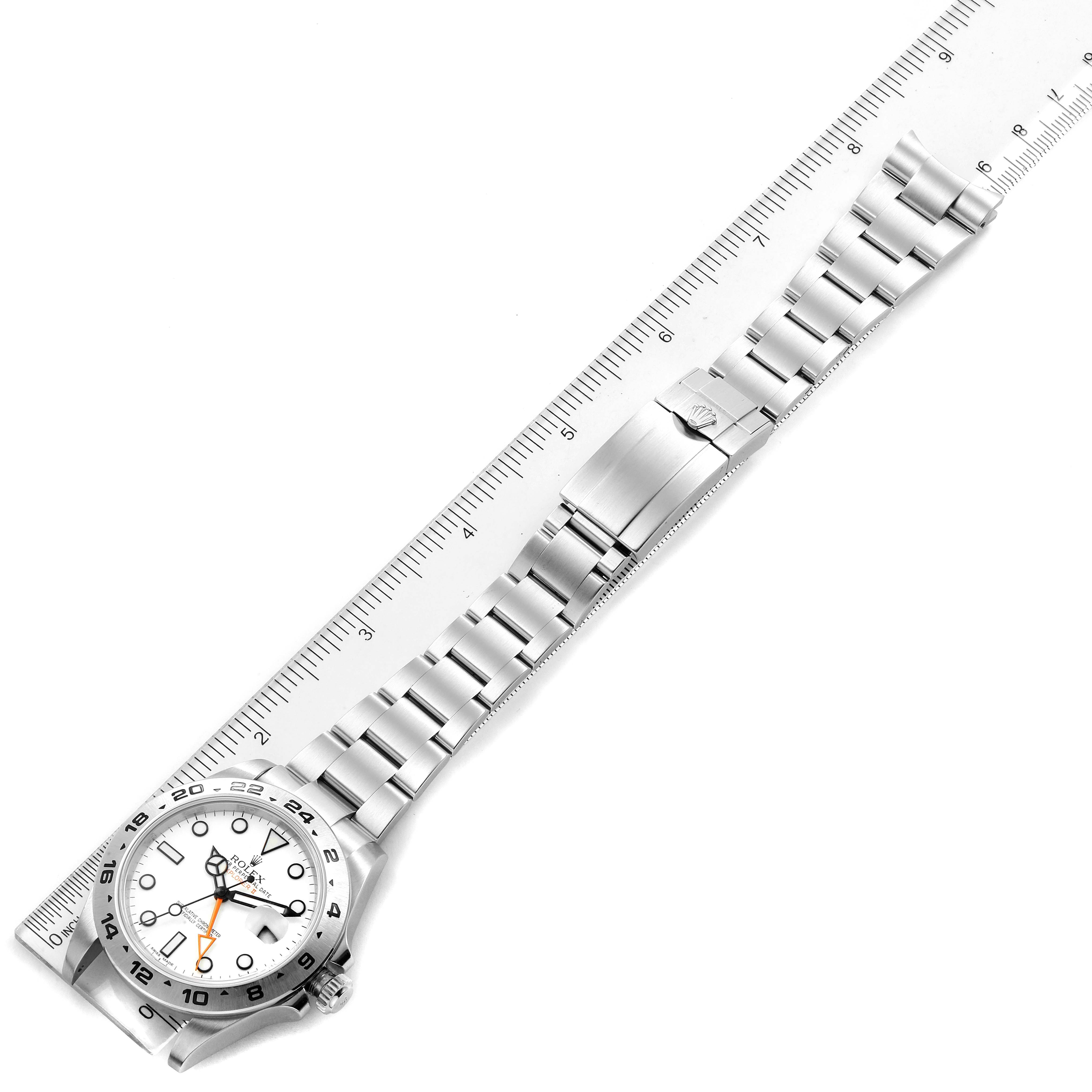 This image shows a top-down view of a Rolex Explorer 216570 Men
s Stainless Steel White Dial 216570 Men
s Stainless Steel White Dial watch, including its face and metal bracelet, alongside a ruler.