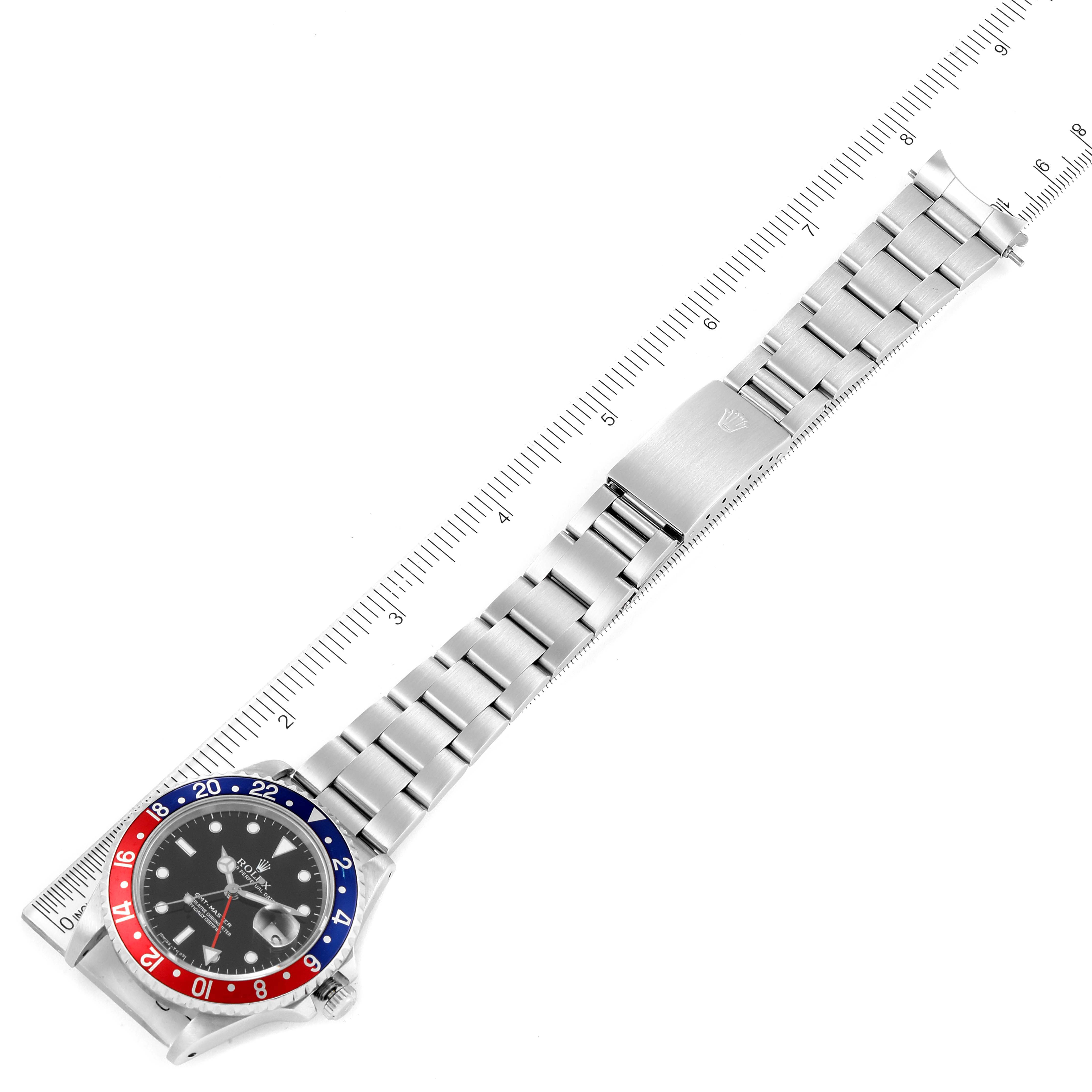 The photo shows the Rolex GMT-Master 16700 Men
s Stainless Steel Black Dial 16700 Men
s Stainless Steel Black Dial watch laid flat with its band extended alongside a ruler for measurement.