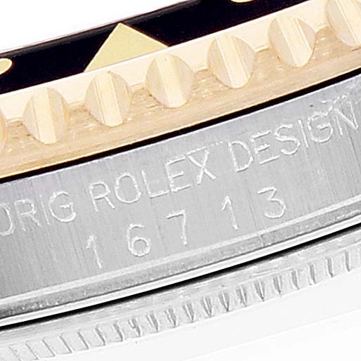 The image shows a close-up of the bezel and casing of a Rolex GMT-Master 16713 Men's Steel and Gold (two tone) Black Dial 16713 Men's Steel and Gold (two tone) Black Dial watch including its etching and serial number.
