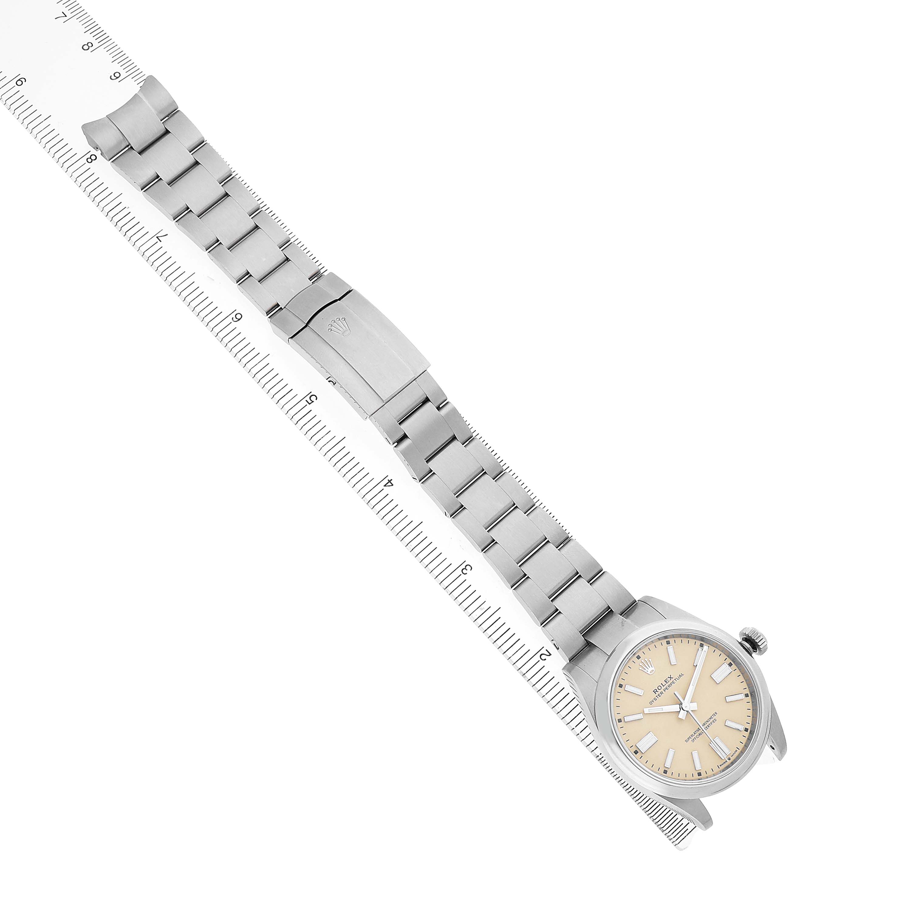 The Rolex Oyster Perpetual 134300 Men's Stainless Steel Beige Dial watch is shown flat with a full view of the bracelet and face next to a ruler.