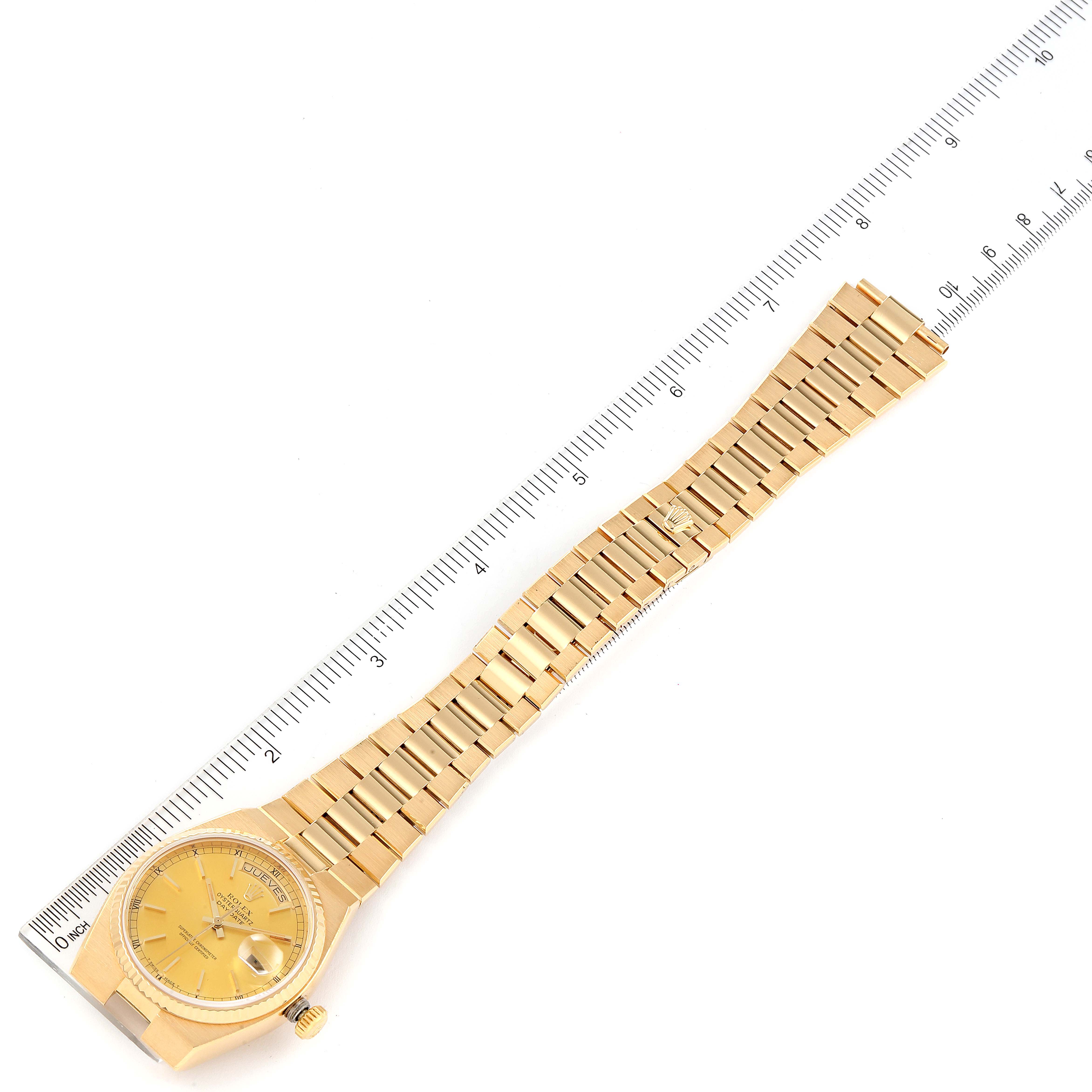 The image shows a Rolex Oysterquartz 19018 Men
s Yellow Gold Champagne Dial 19018 Men
s Yellow Gold Champagne Dial watch, including its dial, bracelet, and a measuring ruler alongside it.