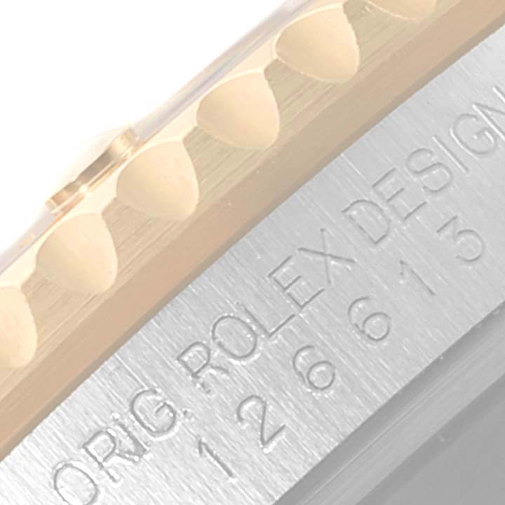 The image shows a close-up of the edge of the bezel and engraved side of a Rolex Submariner 126613 Men
s Steel and Gold (two tone) Blue Dial 126613 Men
s Steel and Gold (two tone) Blue Dial watch.