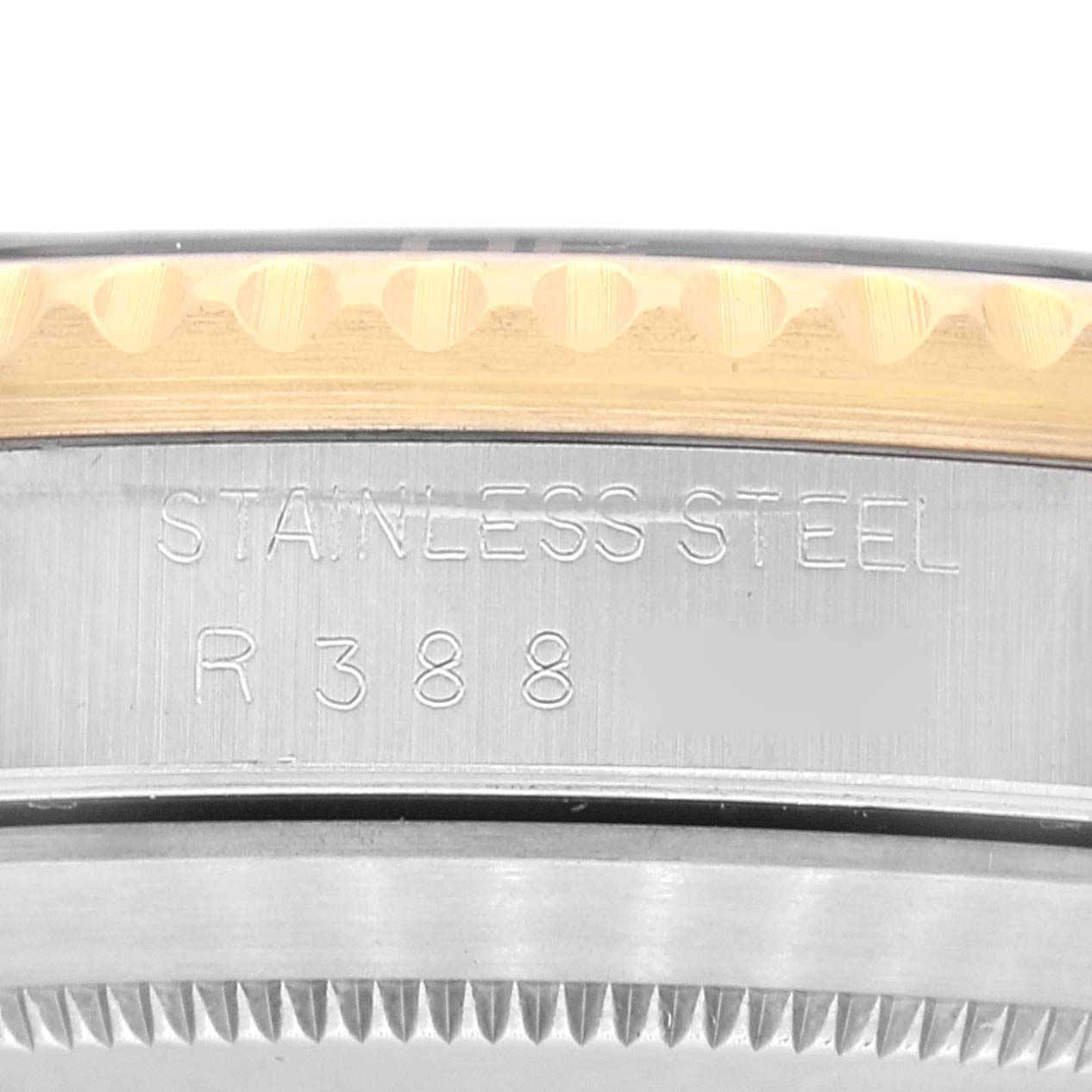 This image shows a close-up of the side of a Rolex Submariner 16803 Men's Steel and Gold (two tone) Black Dial 16803 Men's Steel and Gold (two tone) Black Dial watch case with "STAINLESS STEEL" and "R 3 8 8" engraved on it.