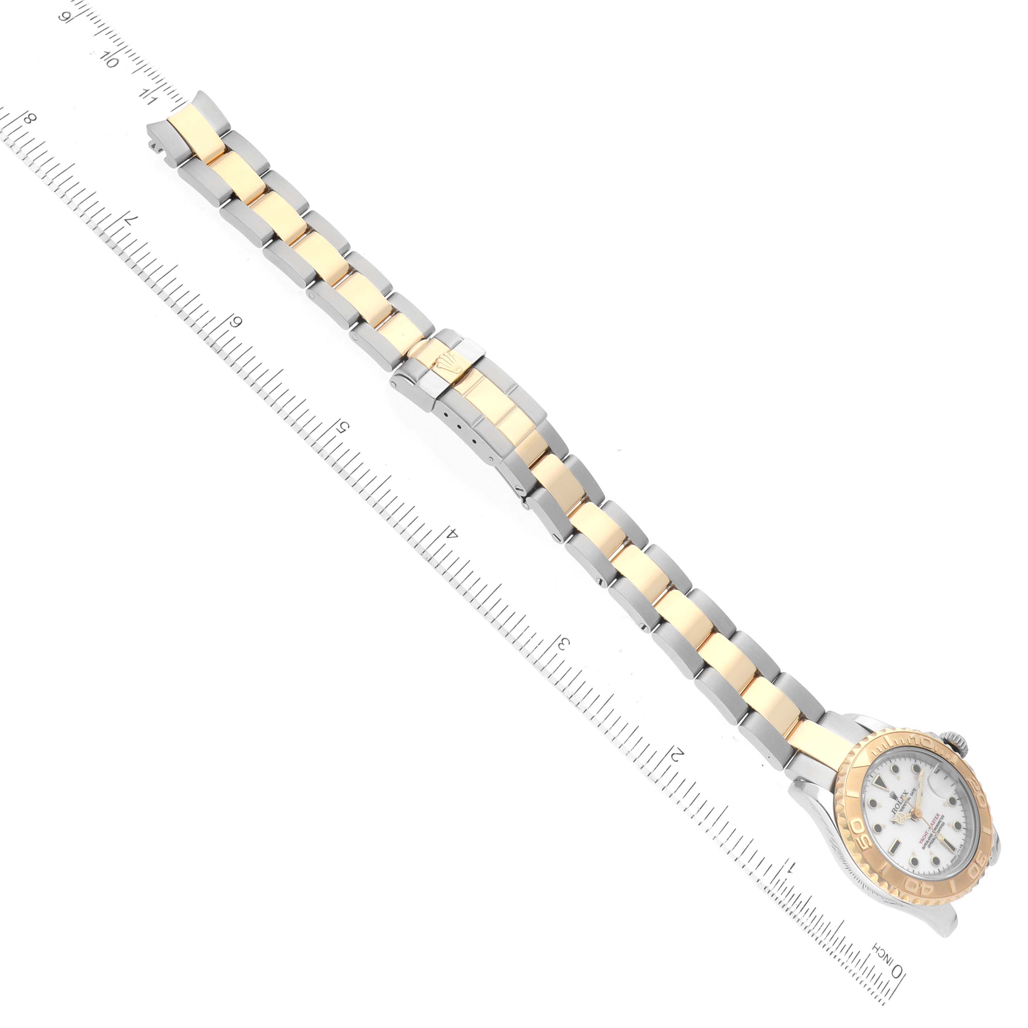 The image shows the Rolex Yacht-Master 69623 Women's Steel and Gold (two tone) White Dial 69623 Women's Steel and Gold (two tone) White Dial watch laid flat with its two-tone bracelet and bezel, alongside a ruler for scale.
