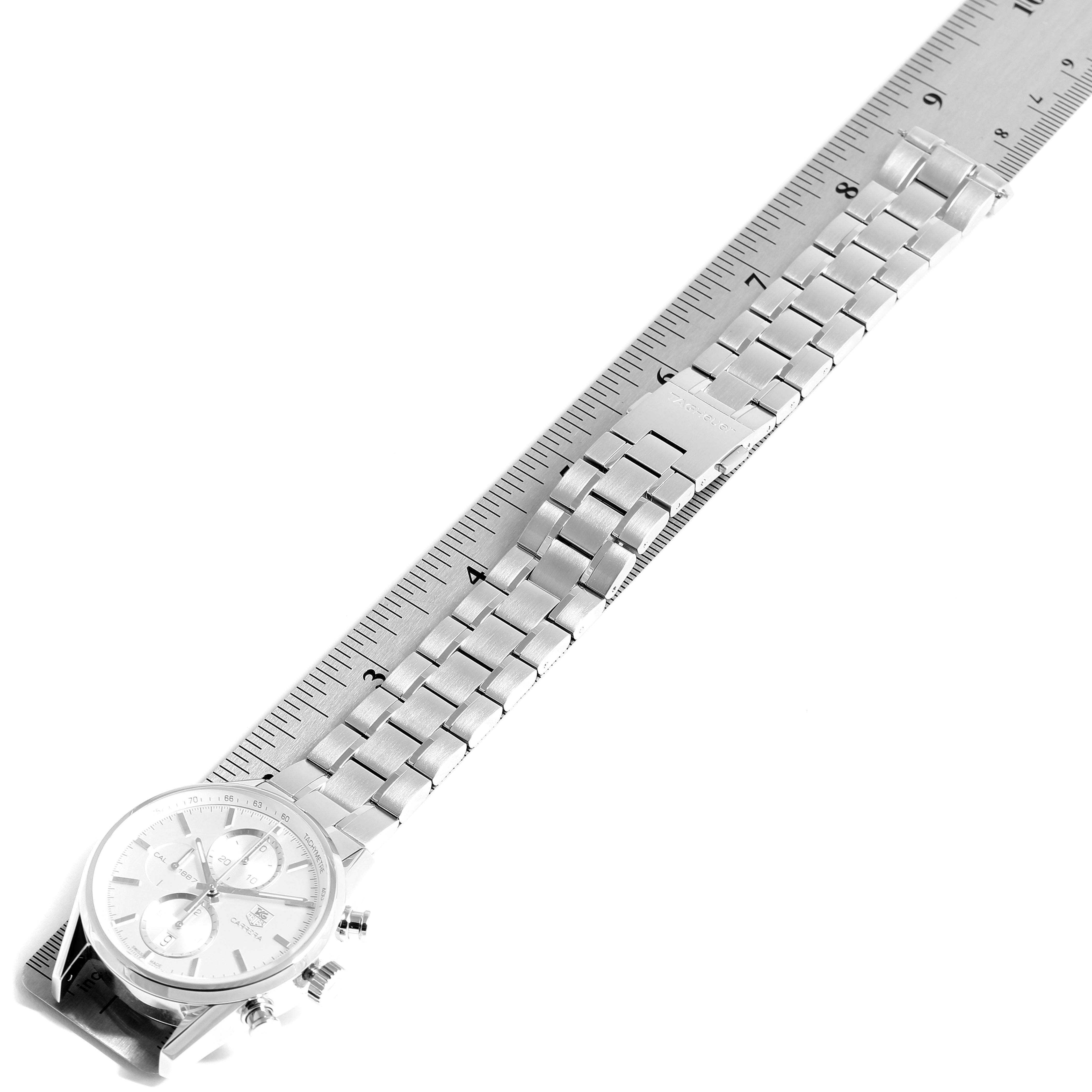 The image shows a top-view angle of a Tag Heuer Carrera CAR2111.BA0720 Men
s Stainless Steel Silver Dial CAR2111.BA0720 Men
s Stainless Steel Silver Dial watch, focusing on its dial and stainless steel bracelet laid against a ruler.