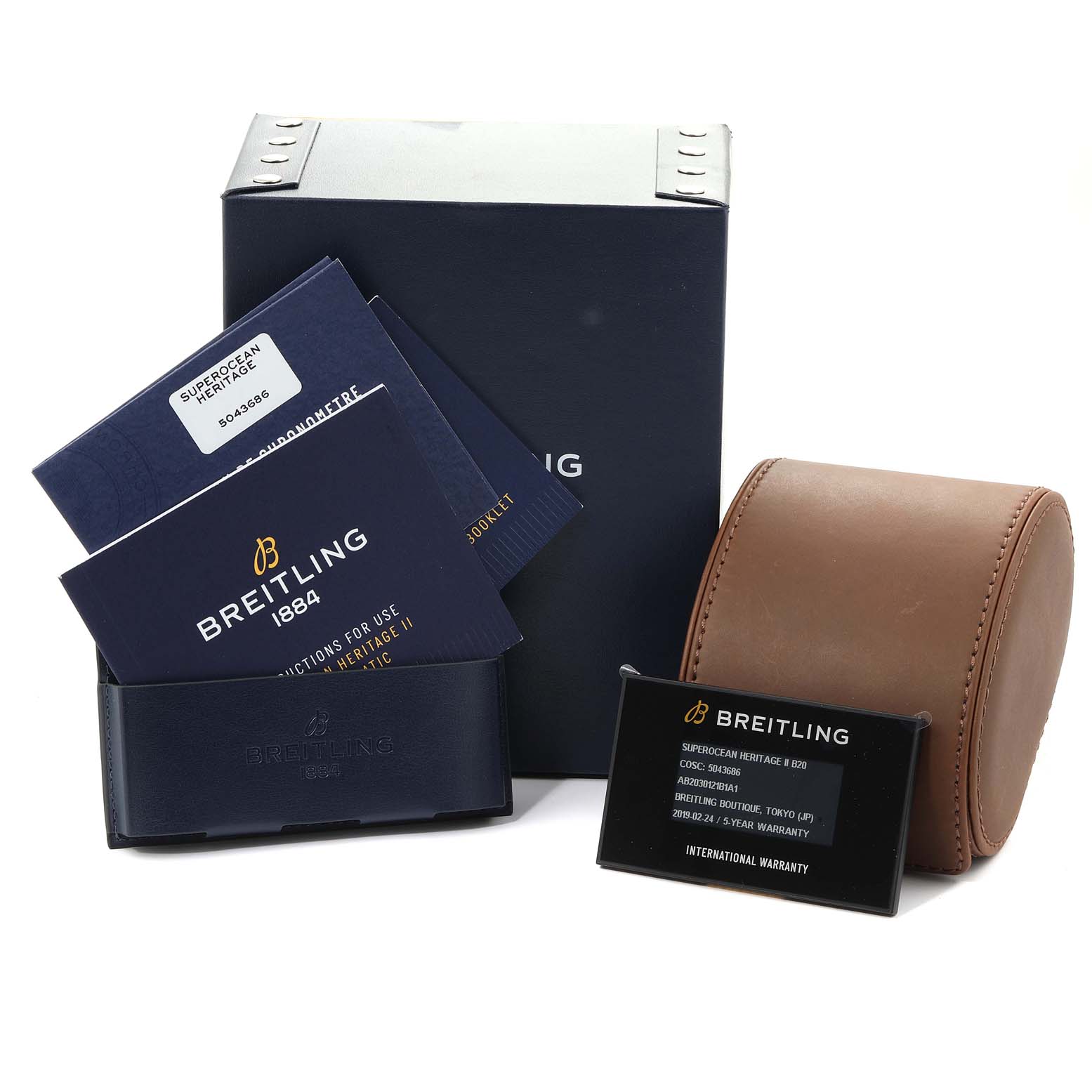 The image shows the packaging and accessories of a Breitling Superocean AB2030 Men's Stainless Steel Black Dial AB2030 Men's Stainless Steel Black Dial watch, including booklets, an international warranty card, and a tan watch case.