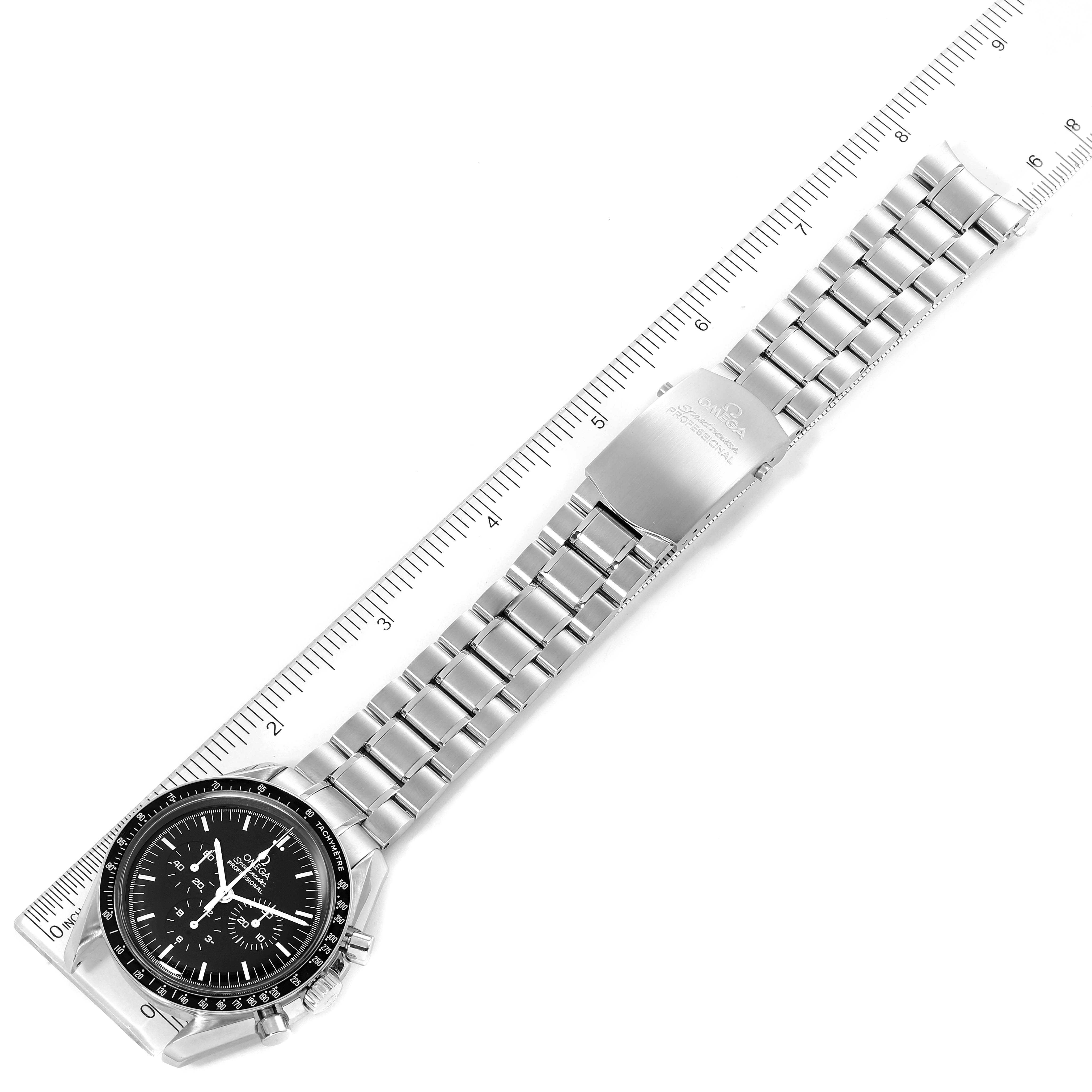 The image shows an Omega Speedmaster 3570.50.00 Men
s Stainless Steel Black Dial 3570.50.00 Men
s Stainless Steel Black Dial watch laid flat against a ruler, displaying the watch face and entire metal bracelet.