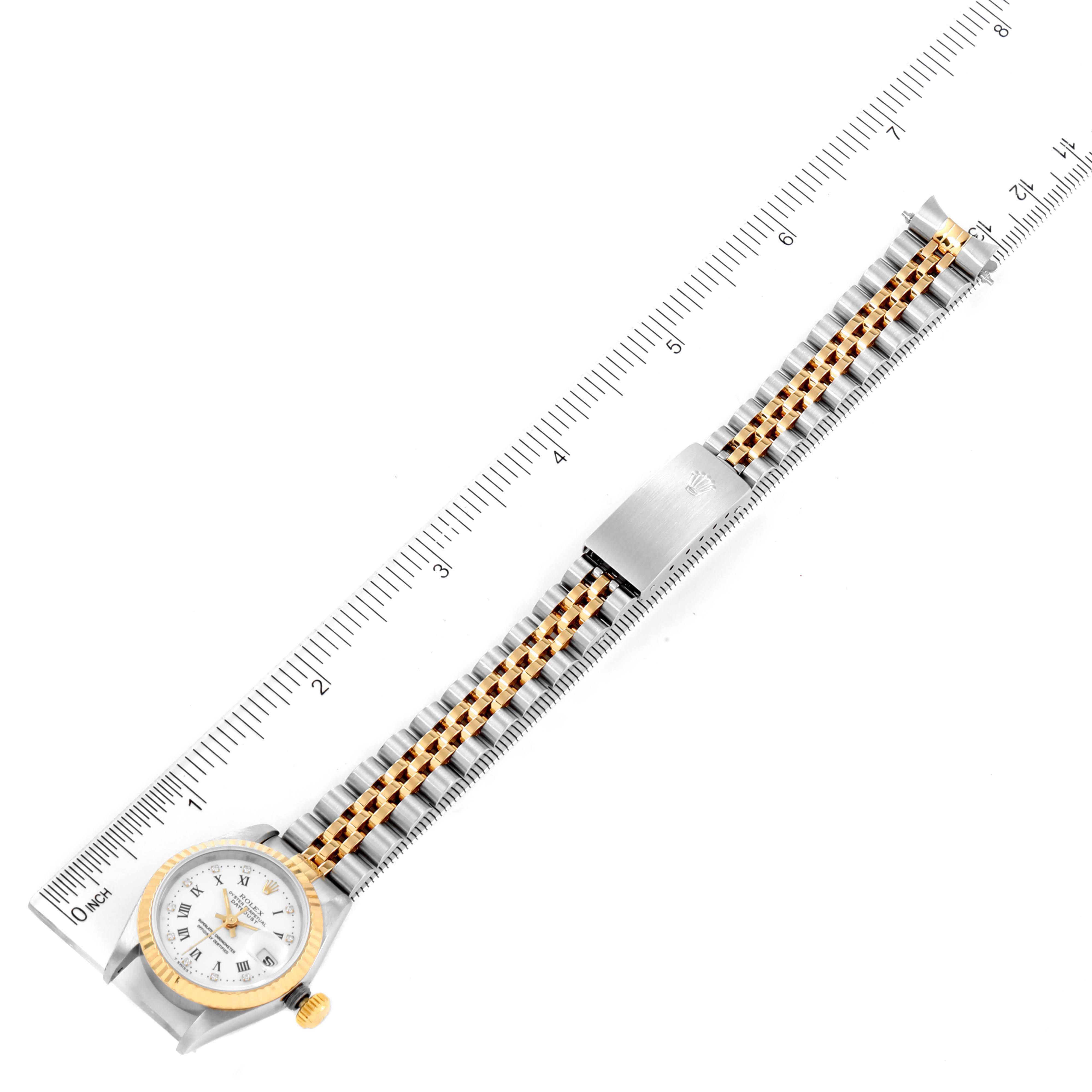 The image shows an overhead view of a Rolex Datejust 69173 Women's Steel and Gold (two tone) White Dial 69173 Women's Steel and Gold (two tone) White Dial watch, displaying its face, bracelet, and clasp alongside a measuring ruler.
