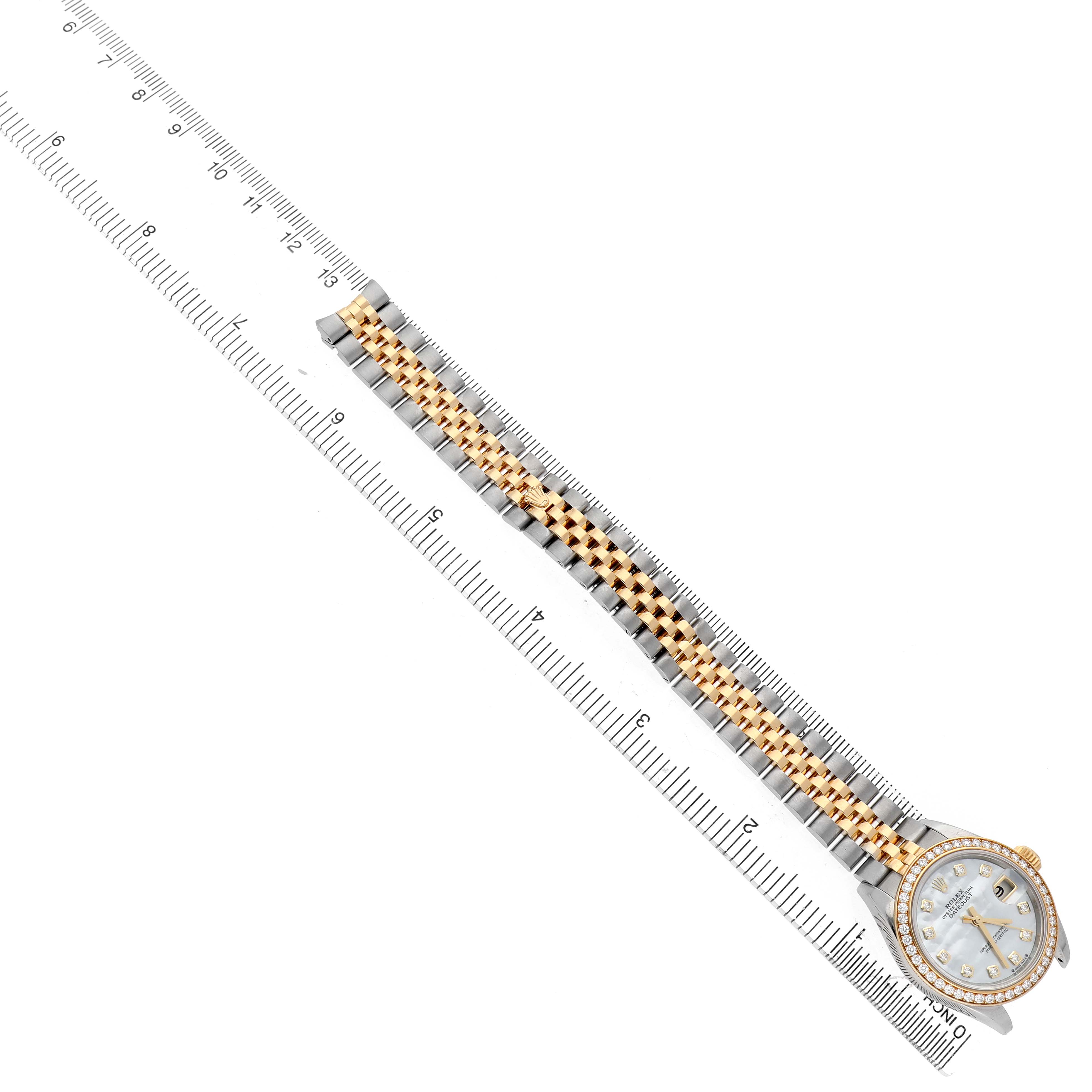 The Rolex Datejust 279383 Women's Steel and Gold (two tone) Mother of Pearl Dial watch is shown at an overhead angle, displaying its case, bracelet, and bezel alongside a measuring ruler.