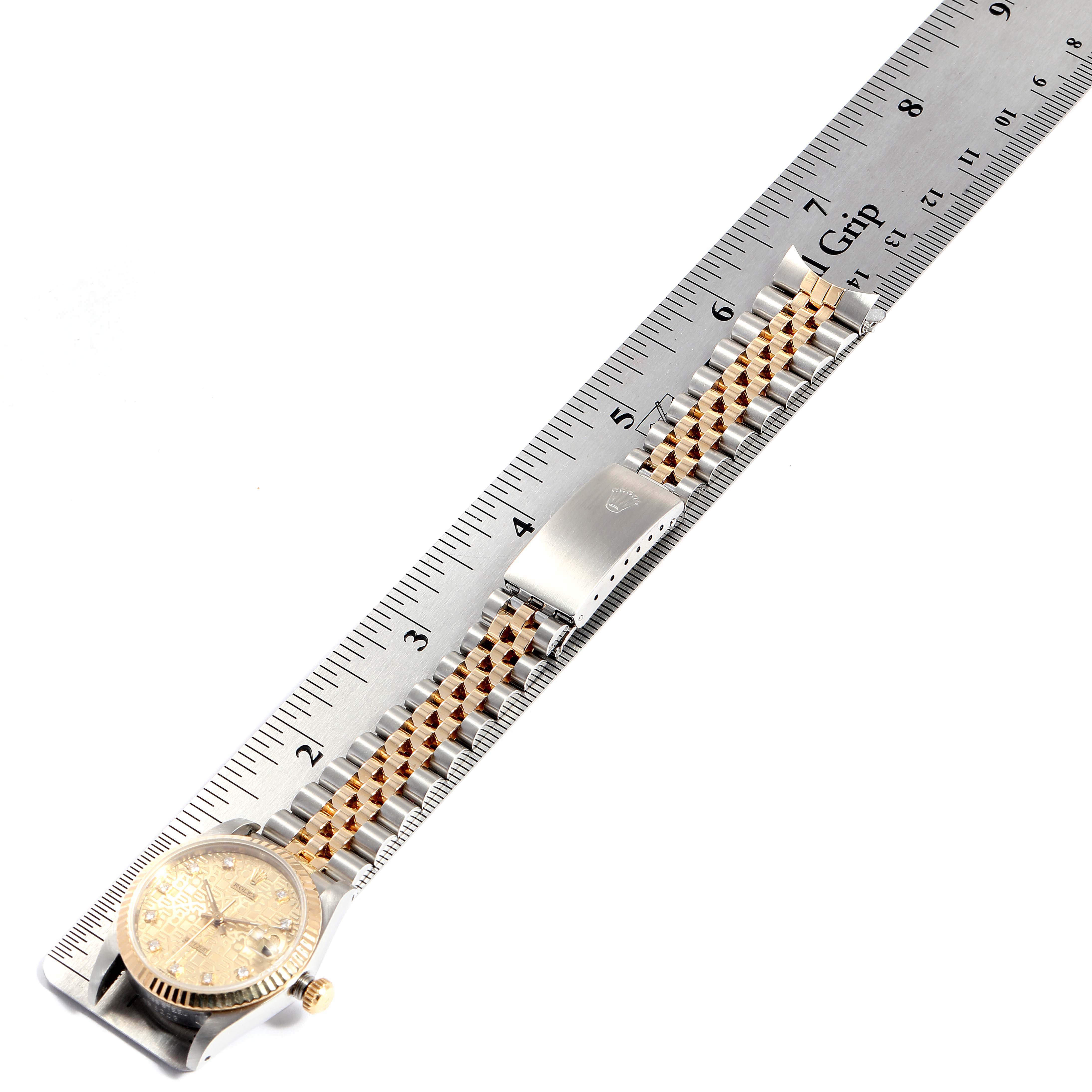 The image shows a Rolex Mid-Size 68273 Women
s Steel and Gold (two tone) Champagne Dial 68273 Women
s Steel and Gold (two tone) Champagne Dial watch laid flat alongside a ruler, displaying its face, band, and clasp.