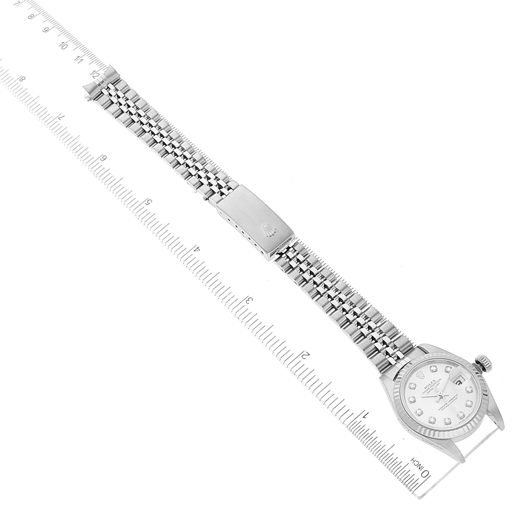 The image shows a top-down view of a Rolex Datejust 79174 Women
s Stainless Steel Silver Dial 79174 Women
s Stainless Steel Silver Dial watch, displaying the face, bracelet, and clasp alongside a measuring ruler.