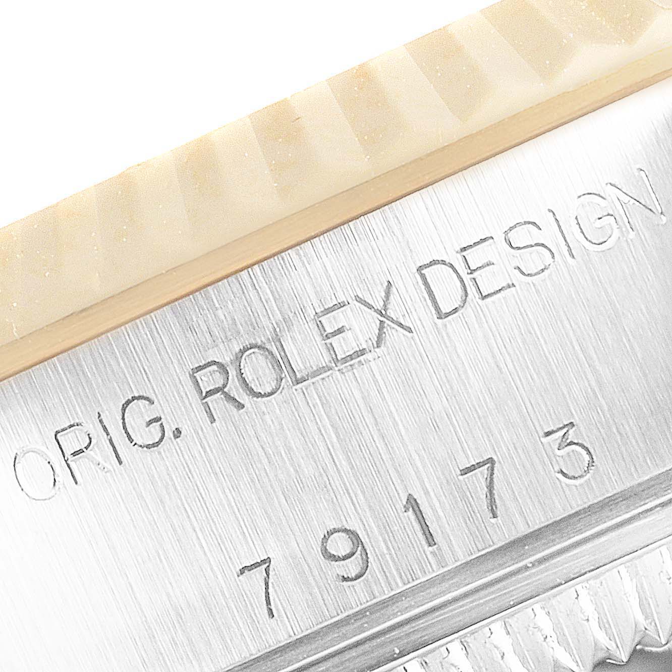 This close-up image of the Rolex Datejust 79173 Women
s Steel and Gold (two tone) Black Dial 79173 Women
s Steel and Gold (two tone) Black Dial shows the case
s engraved "Rolex Design" and part of the fluted bezel.