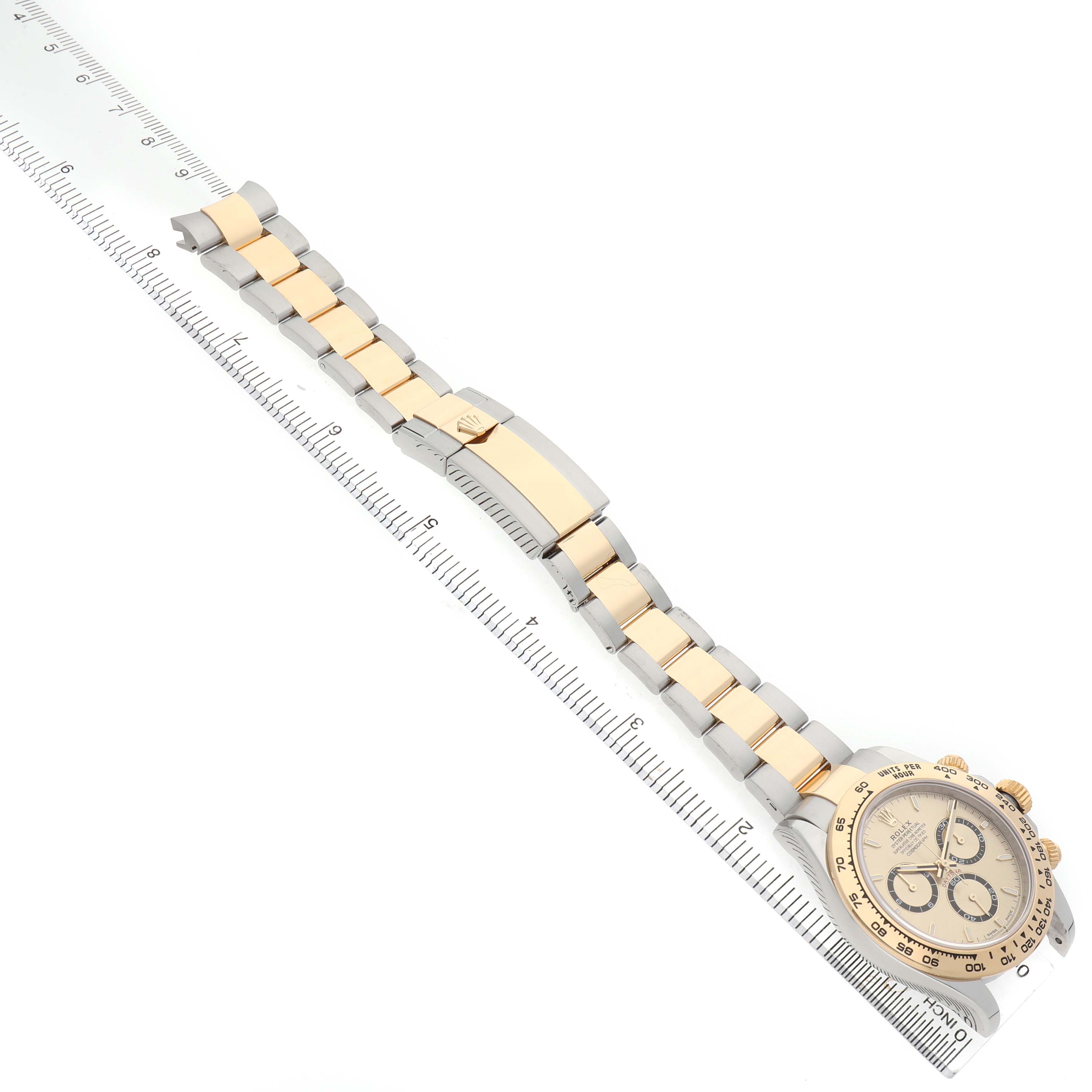 The Rolex Daytona 126503 Men's Steel and Gold (two tone) Champagne Dial watch is shown at an angle revealing the full bracelet and face, placed next to a ruler.