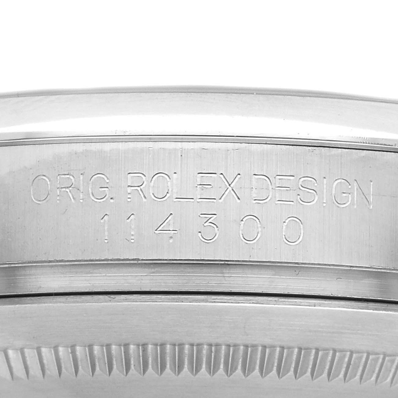 The image shows a side view of the Rolex Oyster Perpetual 114300 Men
s Stainless Steel Grey Dial 114300 Men
s Stainless Steel Grey Dial casing, highlighting its engraved design and model number.