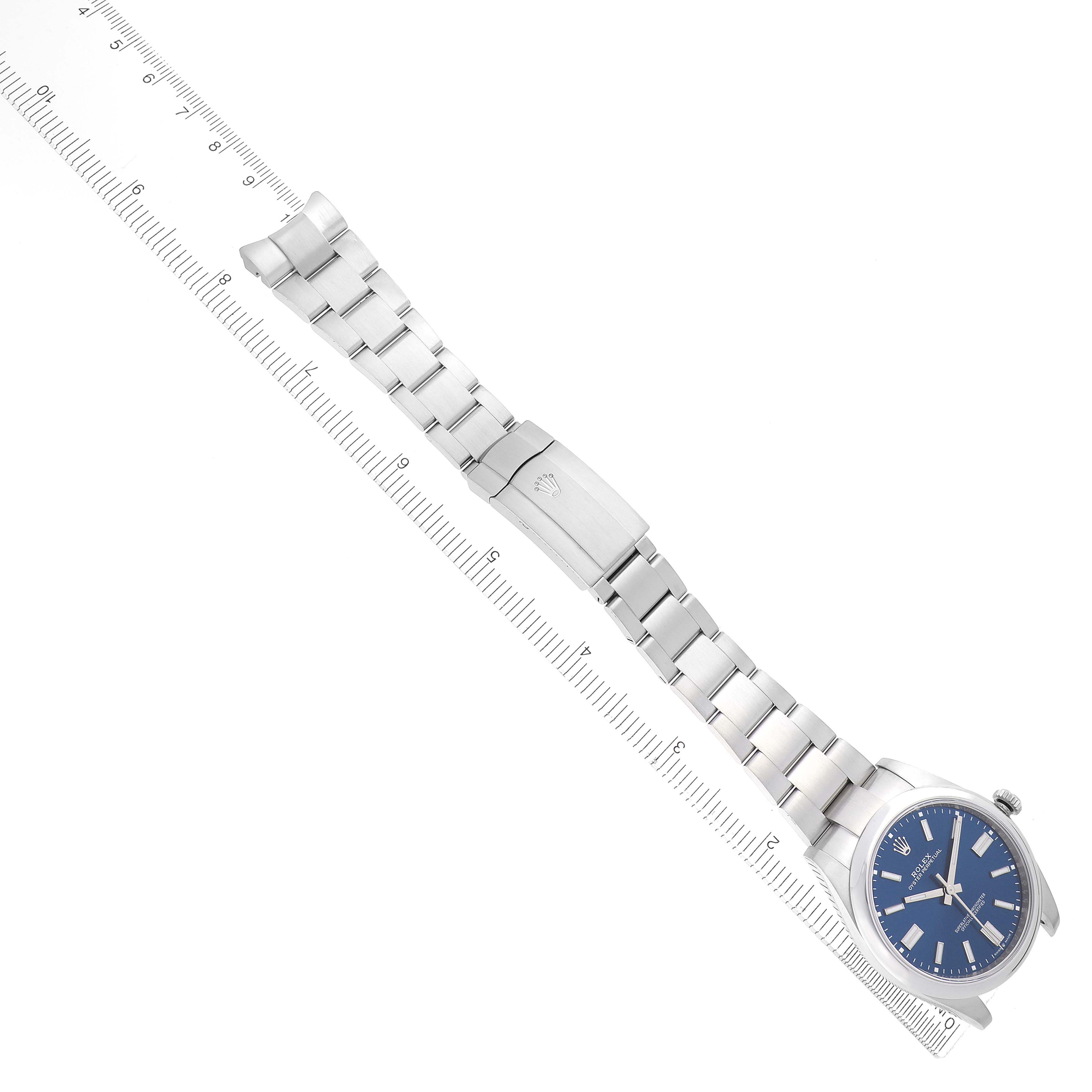 The Rolex Oyster Perpetual 124300 Men
s Stainless Steel Blue Dial 124300 Men
s Stainless Steel Blue Dial watch is displayed diagonally, showcasing the full bracelet and face, with a ruler for scale.