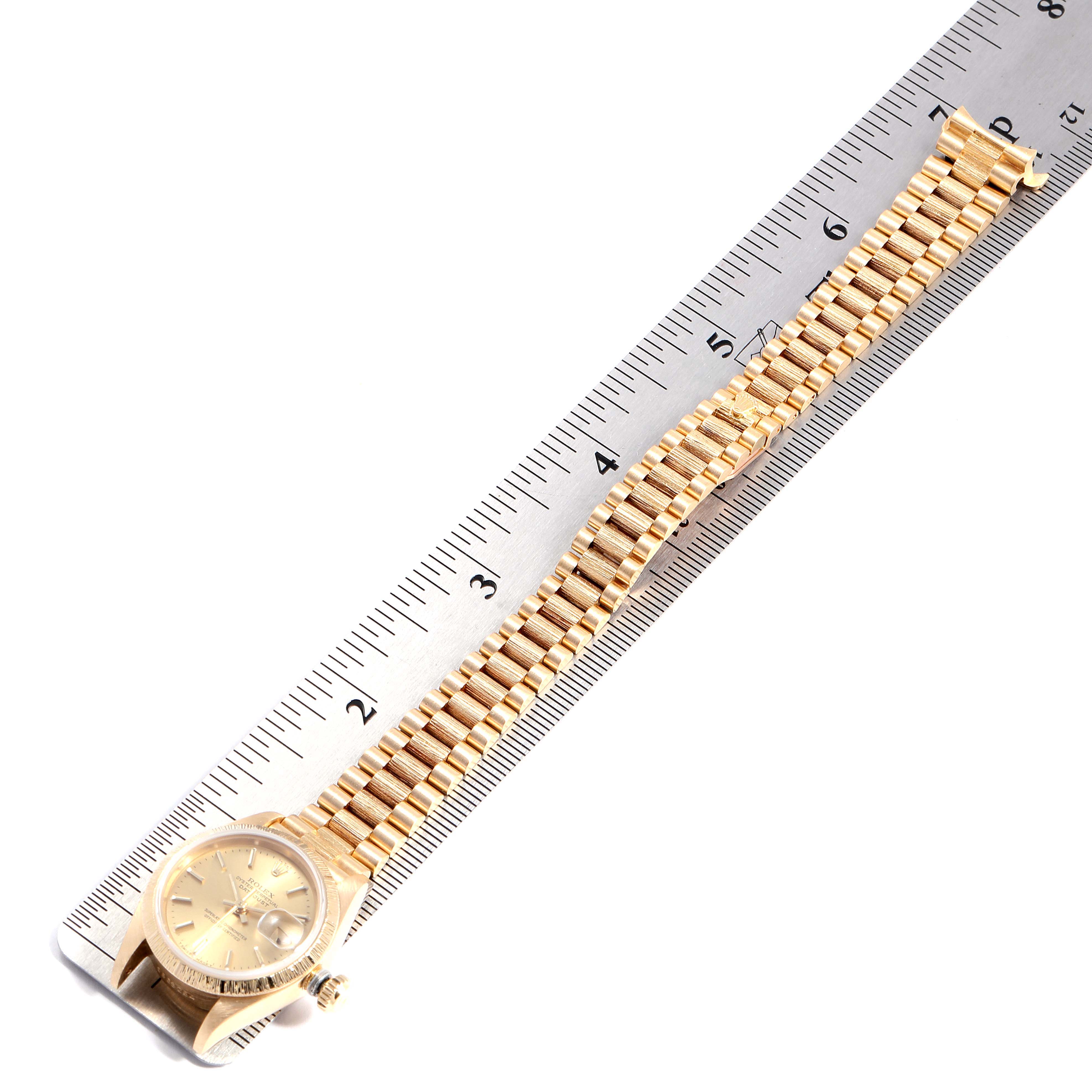 The Rolex President 69278 Women
s Yellow Gold Champagne Dial 69278 Women
s Yellow Gold Champagne Dial model watch is shown at an angle above its chain and face, placed next to a ruler for measurement.