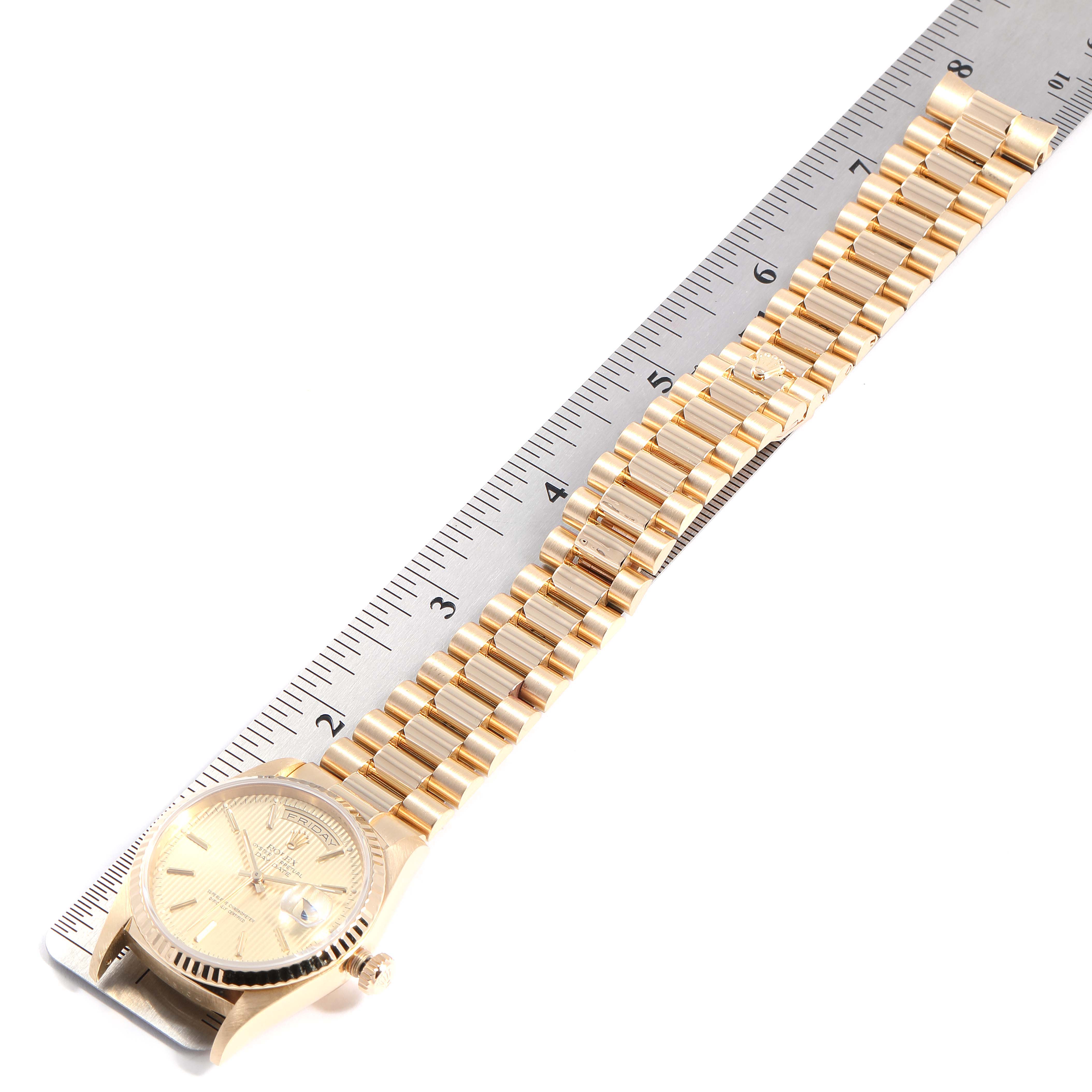 The image shows a Rolex President 18238 Men
s Yellow Gold Champagne Dial 18238 Men
s Yellow Gold Champagne Dial model watch laid flat with a metal bracelet next to a ruler.