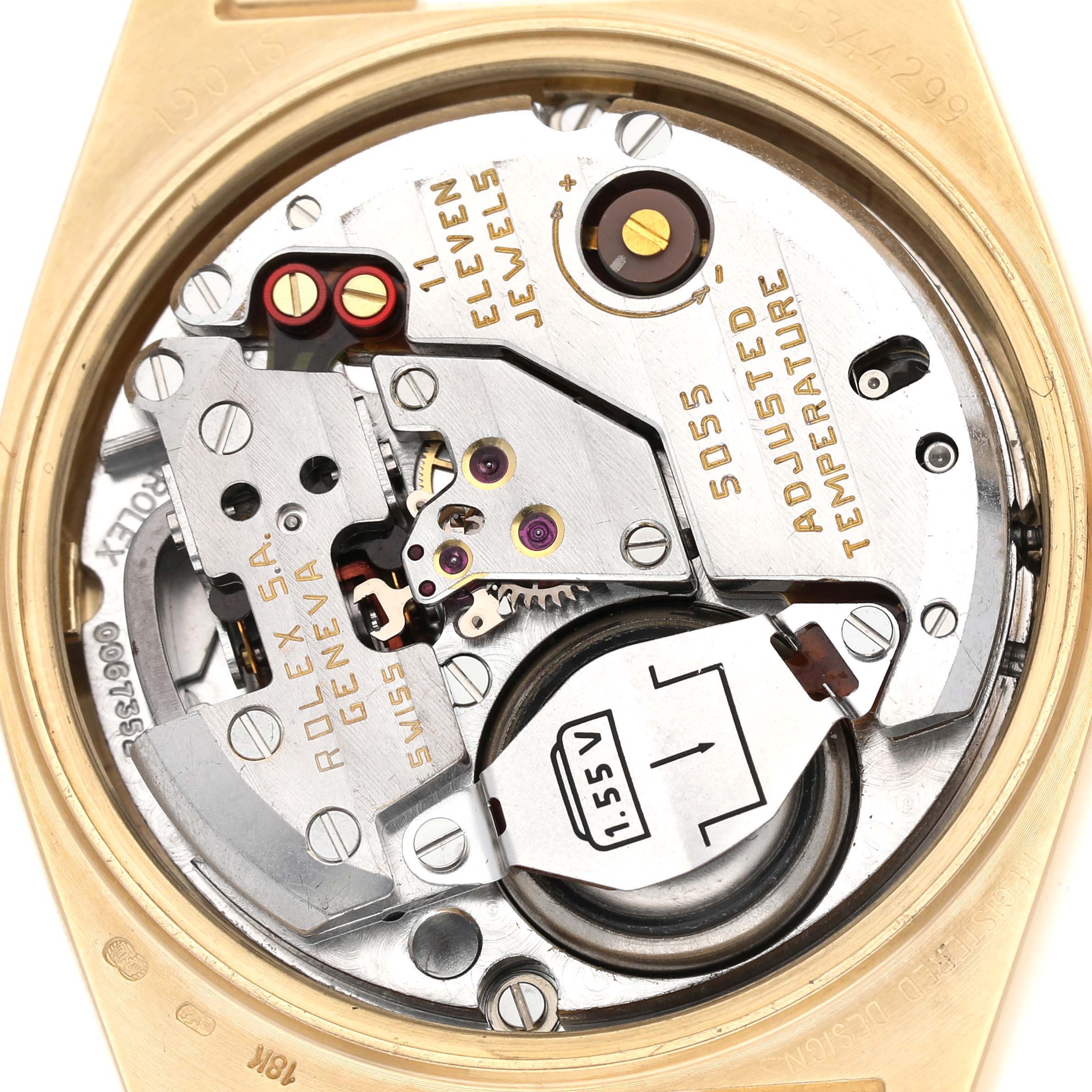 The image shows the internal mechanism of a Rolex Oysterquartz 19018 Men's Yellow Gold Brown Dial watch, focusing on the battery and jewel details from a top-down angle.