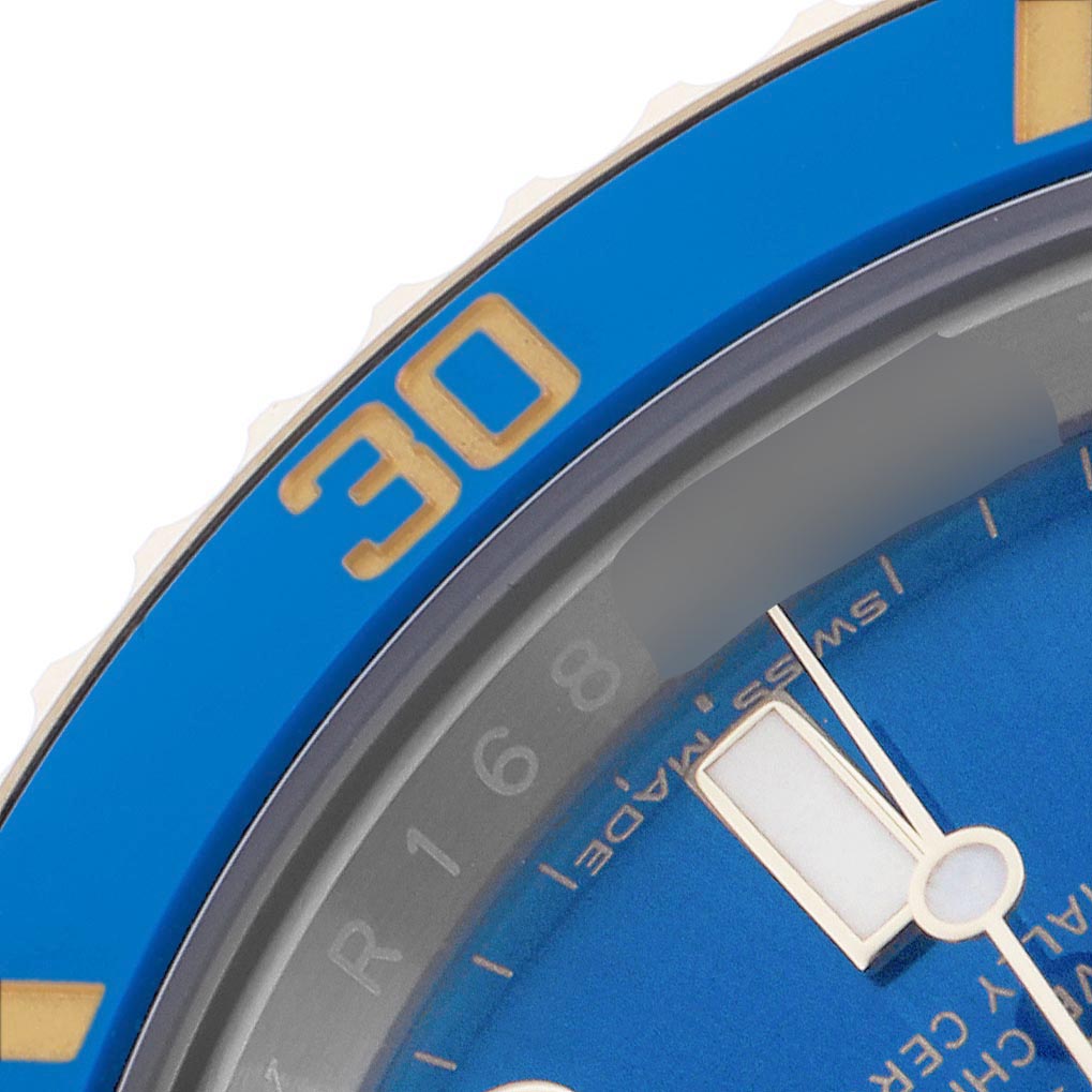 The image shows a close-up of the Rolex Submariner 116613 Men
s Steel and Gold (two tone) Blue Dial 116613 Men
s Steel and Gold (two tone) Blue Dial
s blue bezel and part of the blue dial with gold accents.