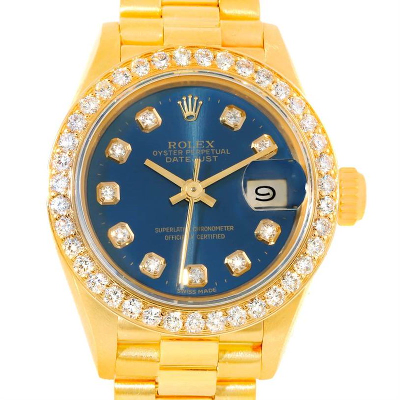 The image shows a front view of the Rolex President model watch, featuring its gold case, diamond bezel, and blue dial with date display.