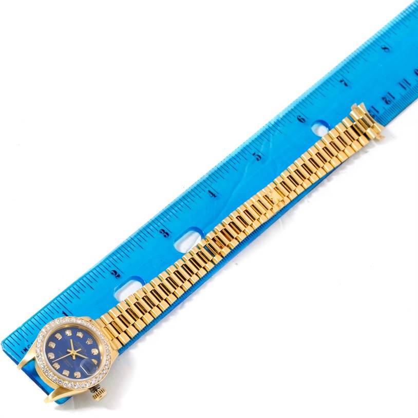 The Rolex President 69178 Women's Yellow Gold Blue Dial 69178 Women's Yellow Gold Blue Dial model watch is positioned flat with its face and entire bracelet shown, measured against a blue ruler.