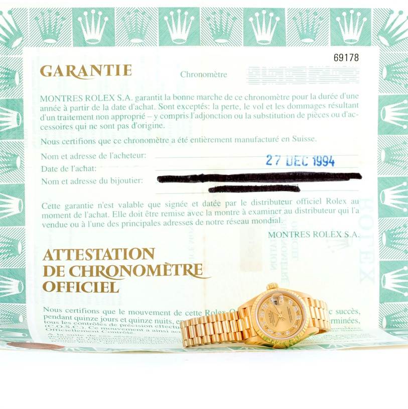 The image showcases a Rolex President 69178 Women's Yellow Gold Champagne Dial 69178 Women's Yellow Gold Champagne Dial model watch laid flat in front of its warranty card.